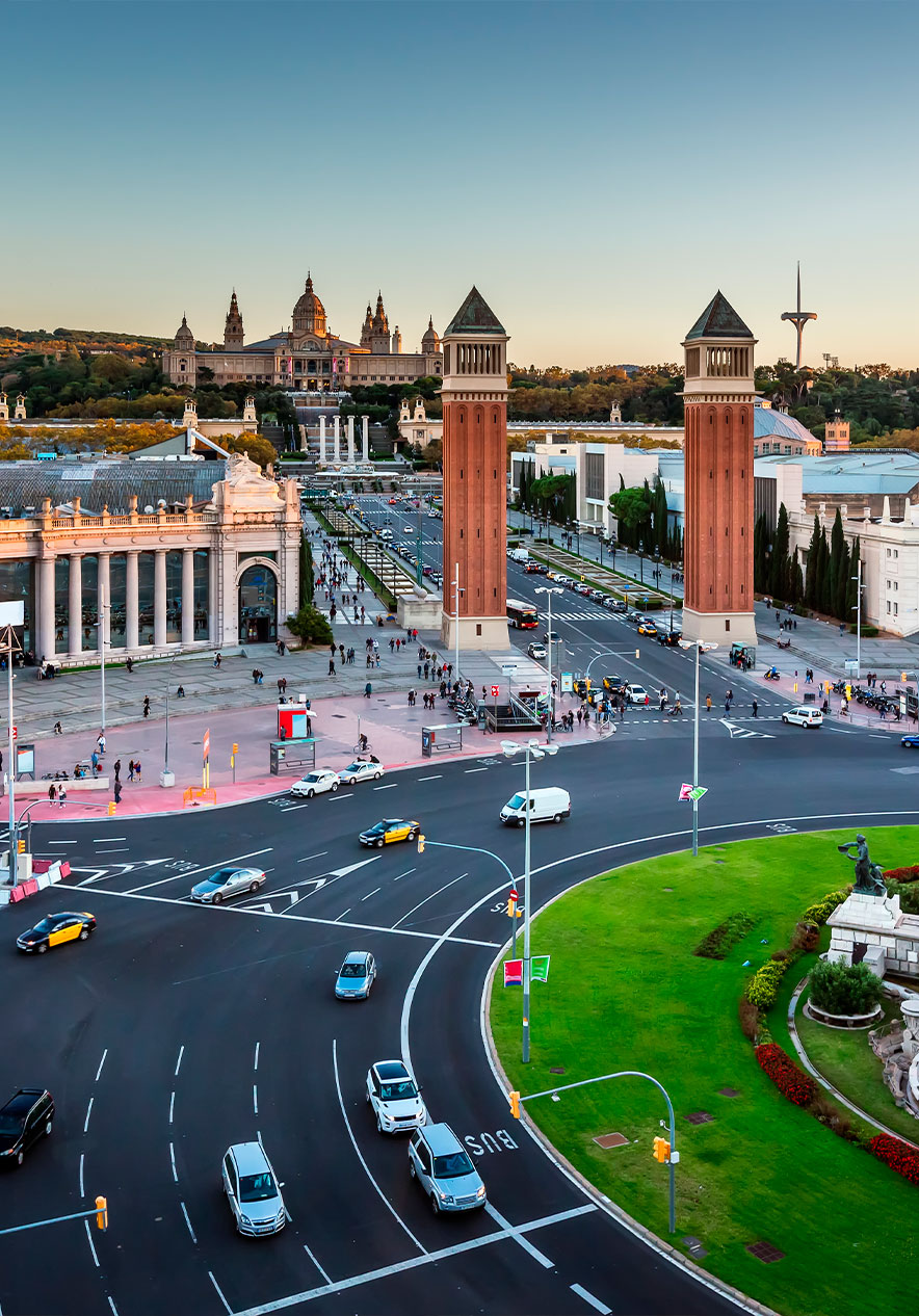 Luchtzicht op Plaça d'Espanya in Barcelona met verkeer, rode torens en het Nationaal Paleis bij zonsondergang