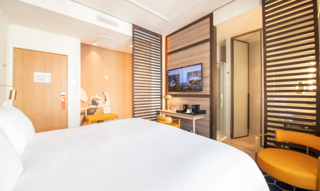 De Legend Room van Pestana CR7 Gran Vía Madrid heeft een tweepersoonsbed, stoel en lamp, twee banken en een houten scheiding