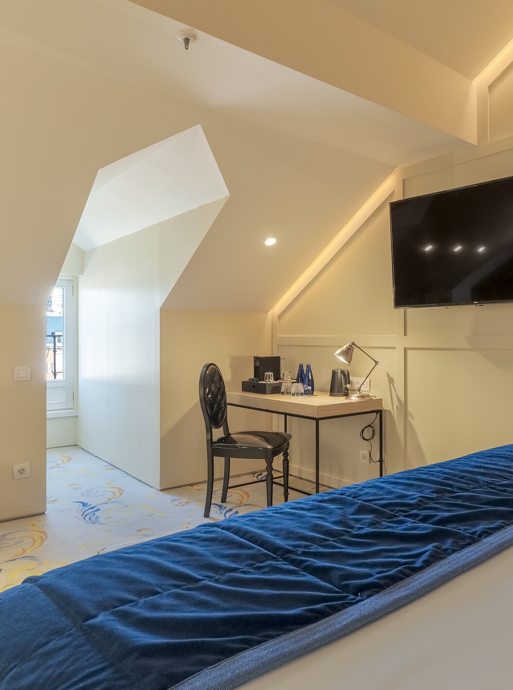 Loft Zolder van Pestana Collection Plaza Mayor met schuin plafond, bureau, wandtelevisie en bed bij raam