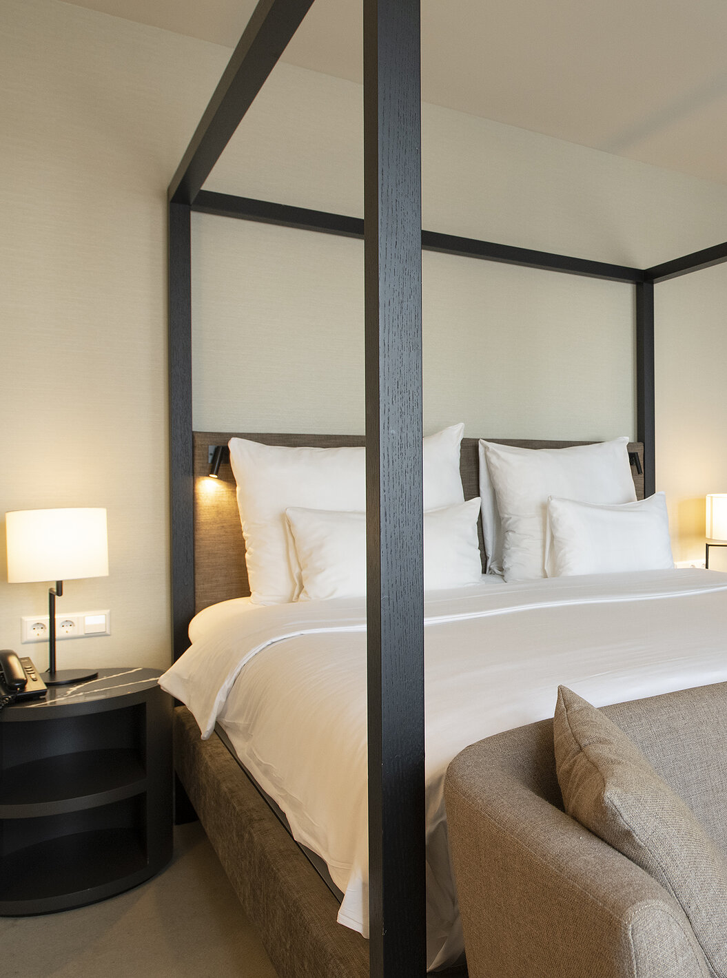 De Premium Deluxe kamer van Pestana Amsterdam Riverside heeft een tweepersoonsbed met hemel, nachtkastje en een bank