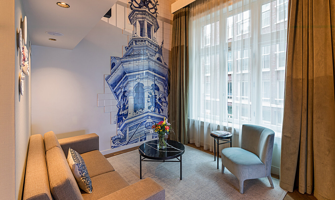 Suite Mezzanine van Pestana Amsterdam Riverside heeft woonkamer met bank, salontafel met bloemen en tegels