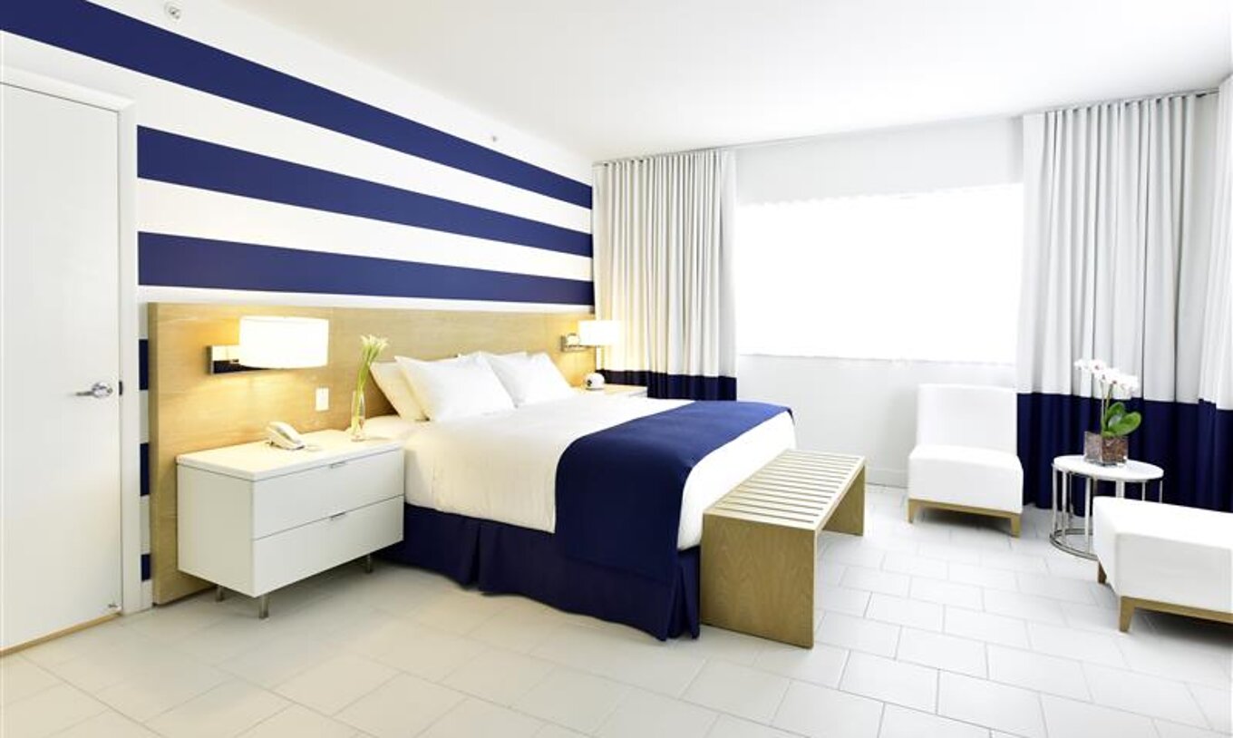 Moderne kamer met tweepersoonsbed, blauw-witte decoratie en daglicht.