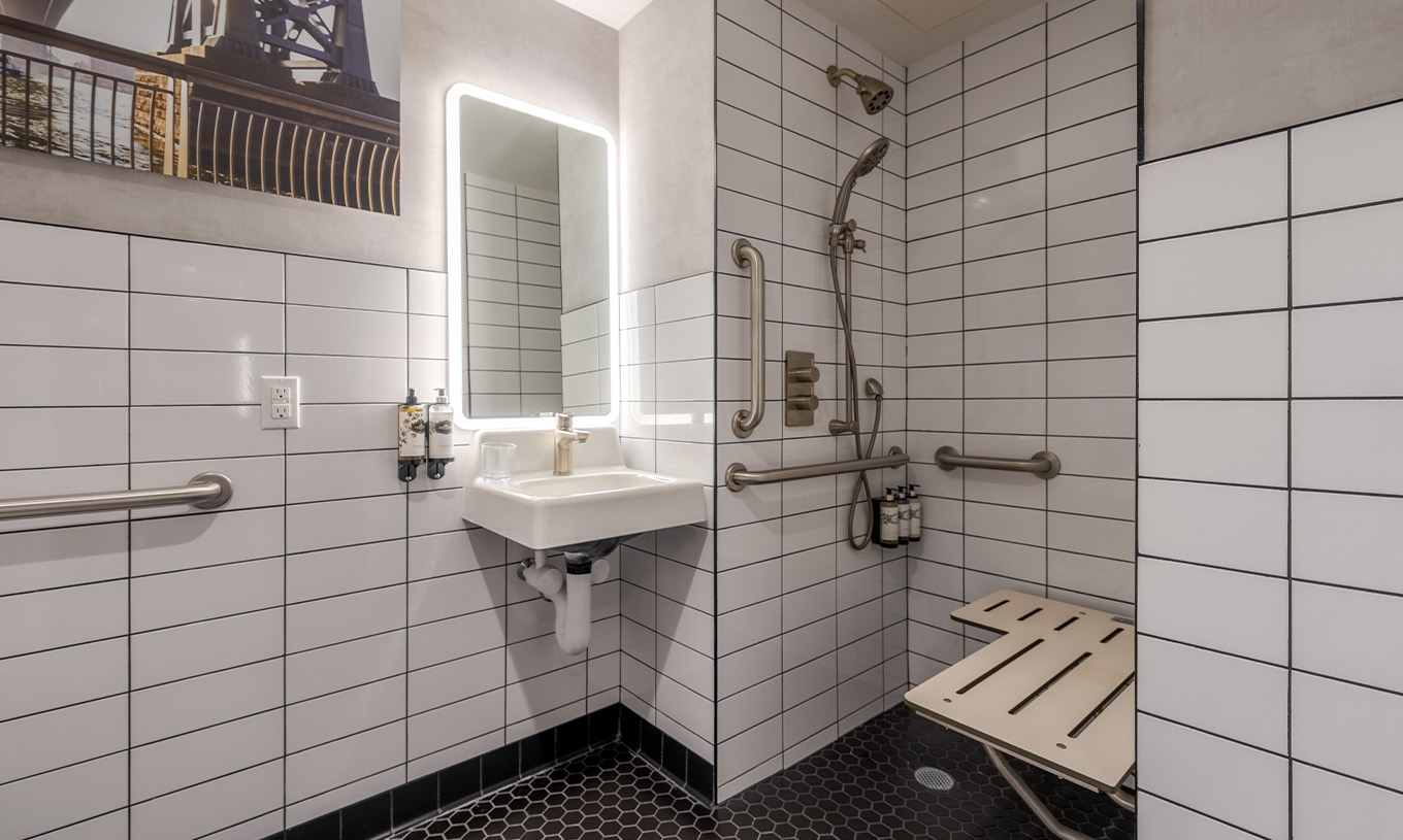 De Comfort ADA van Pestana CR7 Times Square heeft een aangepaste badkamer met douche, wastafel en spiegel