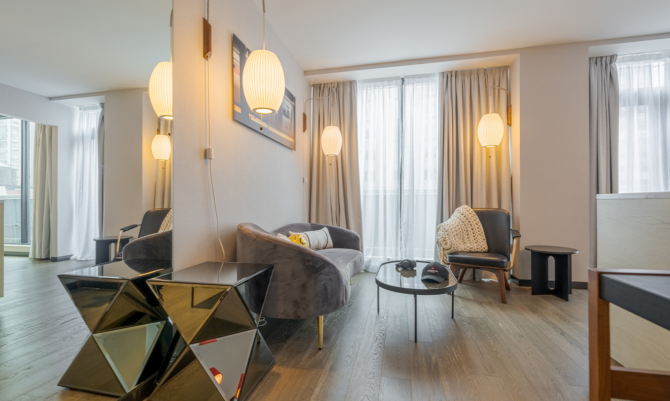 Een Junior Suite met Balkon en Uitzicht van Pestana CR7 Times Square heeft een woonkamer met een bank, grote ramen en stoel