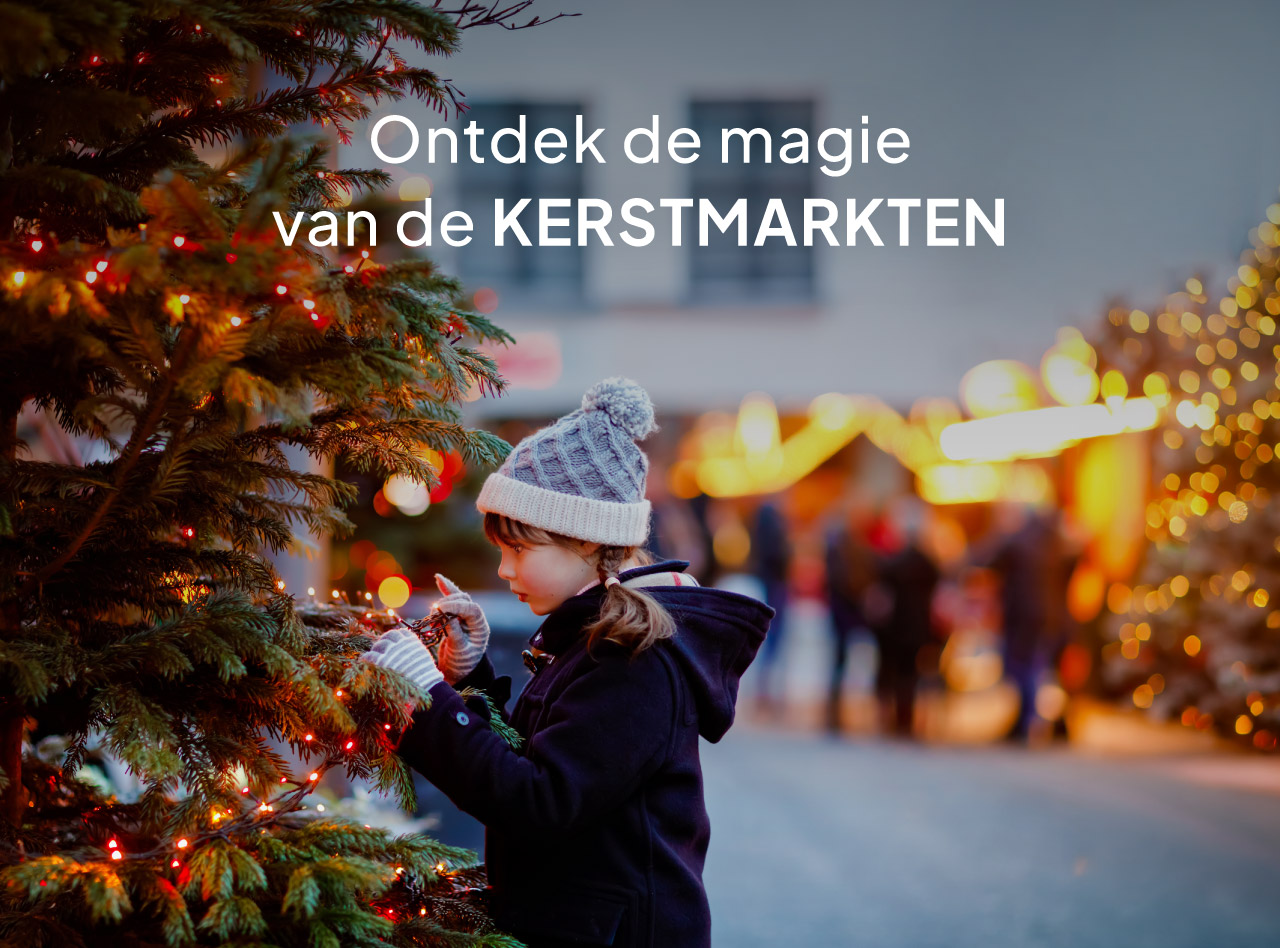Kind met wintermuts versiert verlichte kerstboom op sfeervolle kerstmarkt met warme lichtjes in de avond