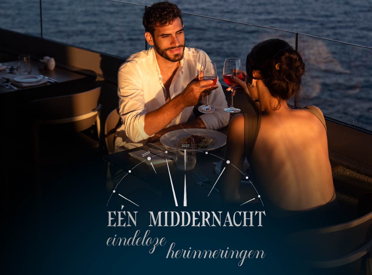 Koppel heft glazen rode wijn tijdens diner bij zonsondergang op terras met uitzicht over rustig water