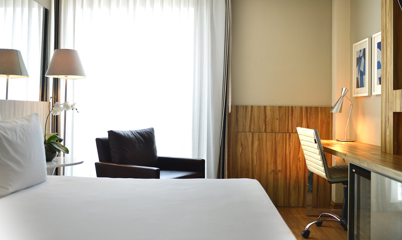 O Quarto Standard Twin do Pestana Rio Atlântica tem uma cama de casal, uma poltrona e uma secretária com cadeira confortável