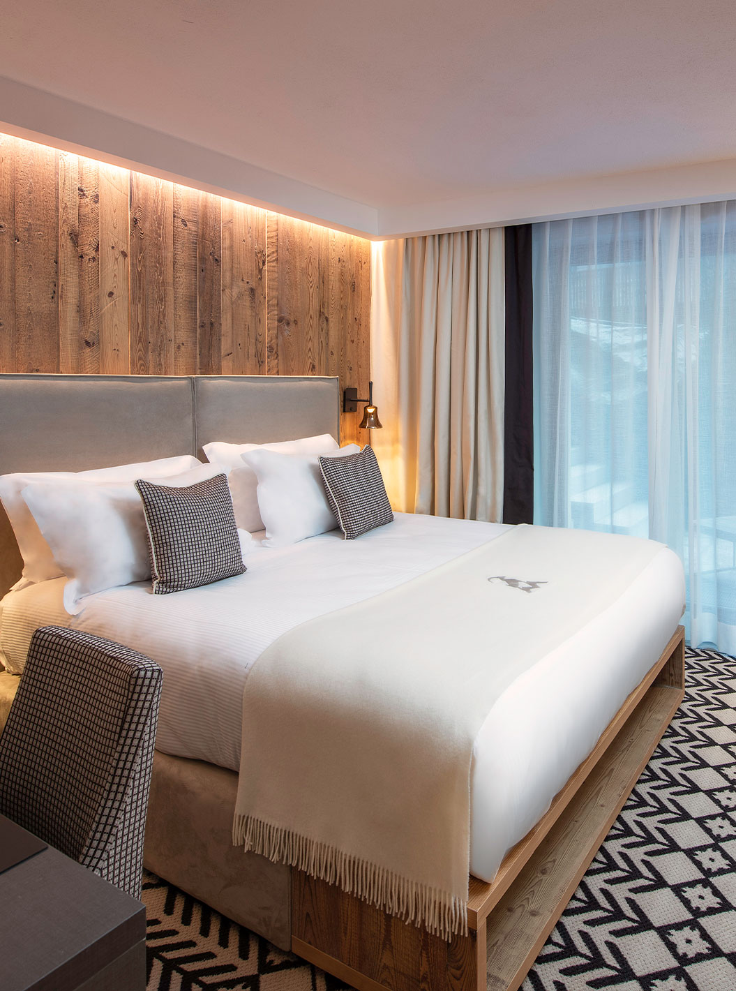 Quarto Clássico no Le Massif Courmayeur com cama de casal, parede em madeira e janela com cortinas claras