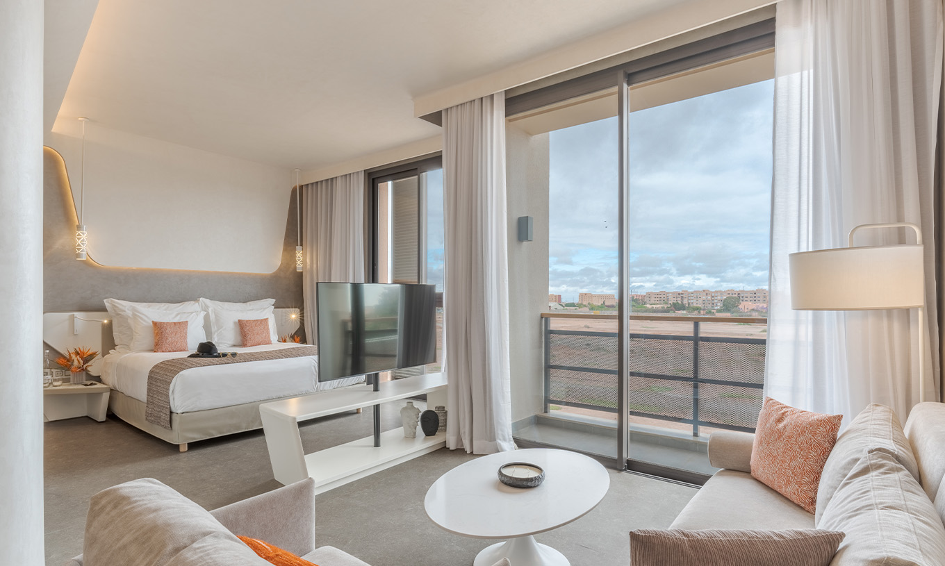 A CR7 Junior Suite do Pestana CR7 Marrakech tem uma varanda e uma zona de estar dentro do quarto, com sofás e televisão