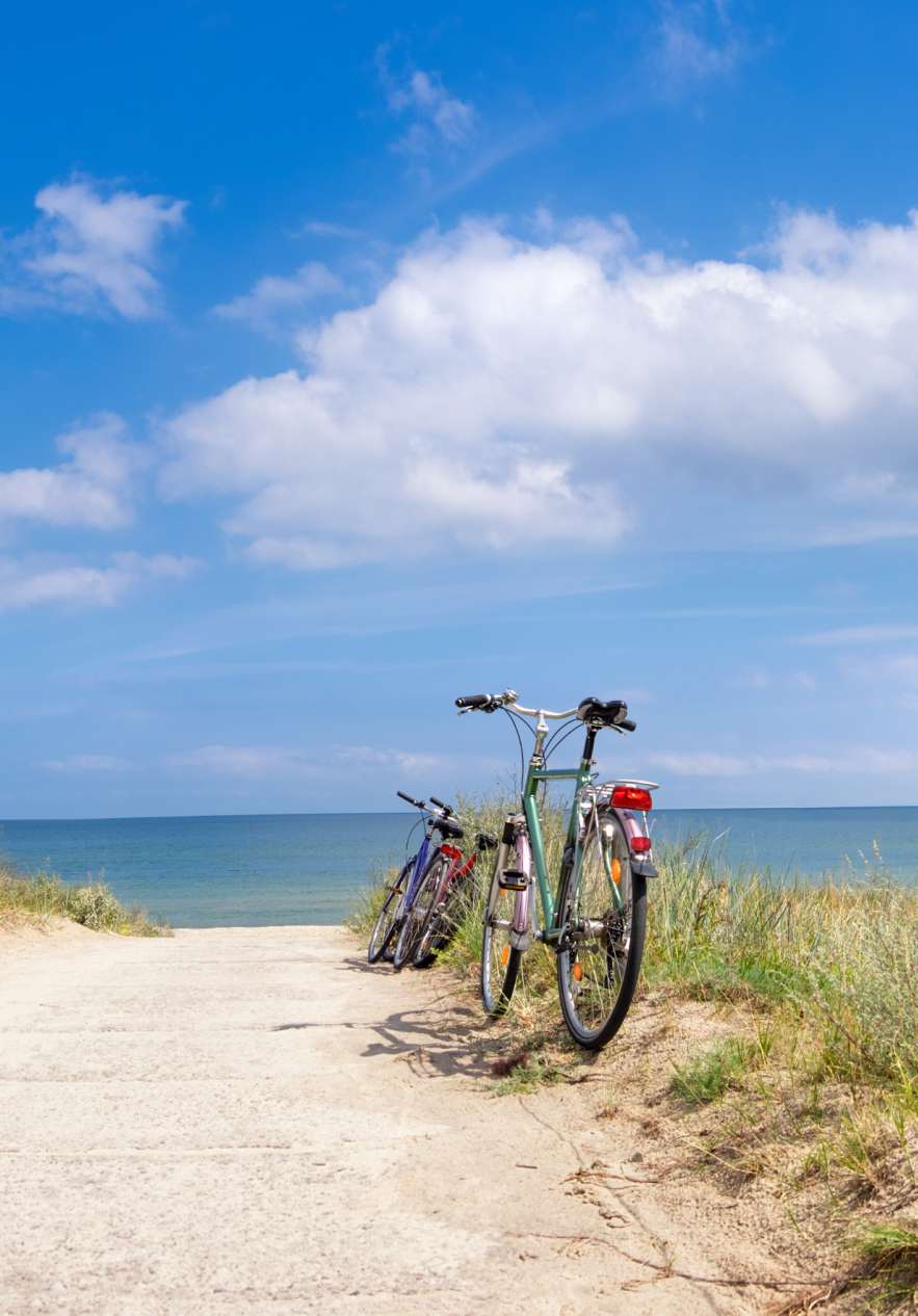 Passeio de bicicleta à beira-mar perto do Pestana Tróia, Villas e Apartamentos em Tróia sob céu azul com nuvens