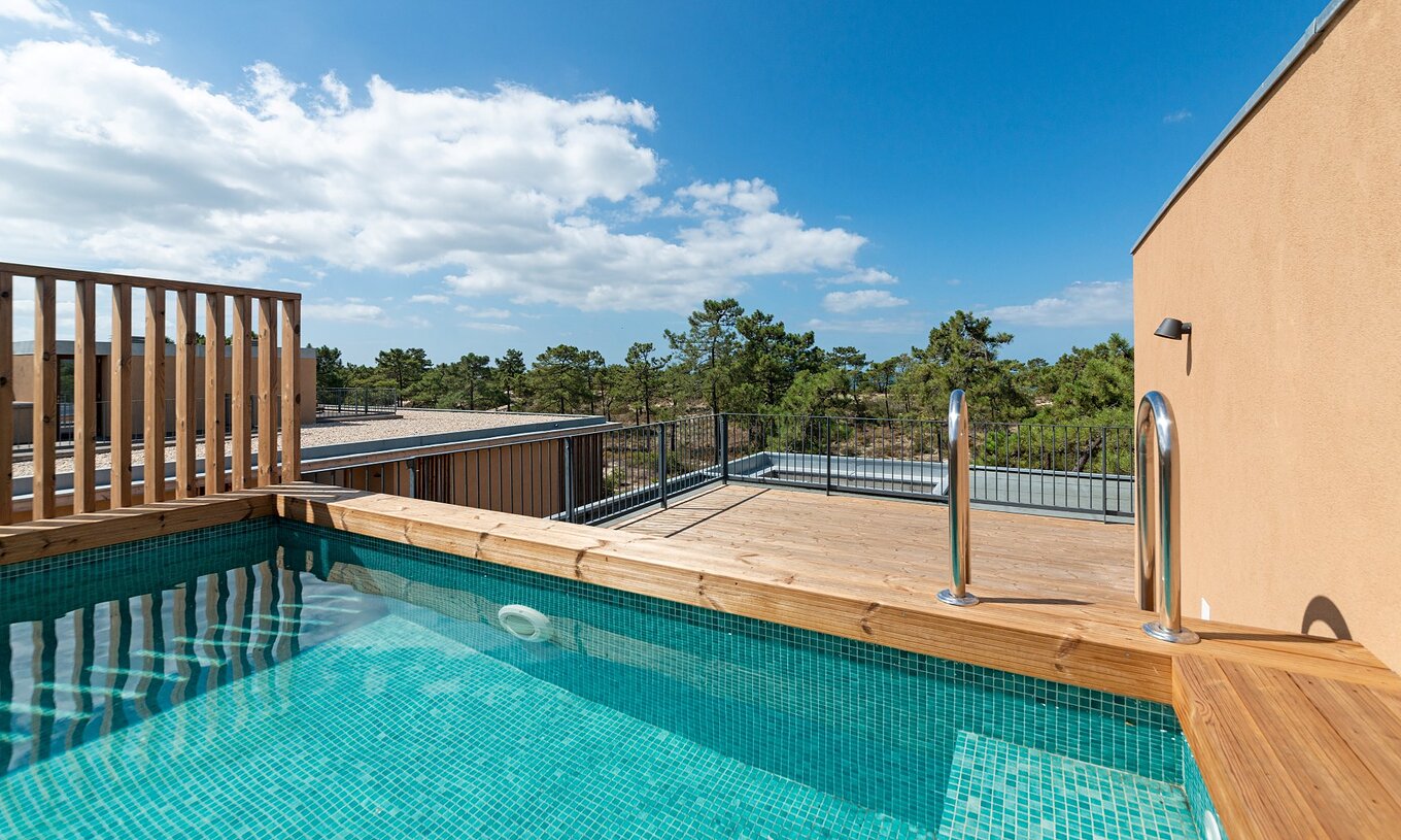 Apartamento Eco Village 1º Andar Vistas com Piscina do Pestana Tróia, exibindo uma piscina privativa em deck de madeira com vista para árvores sob céu azul claro