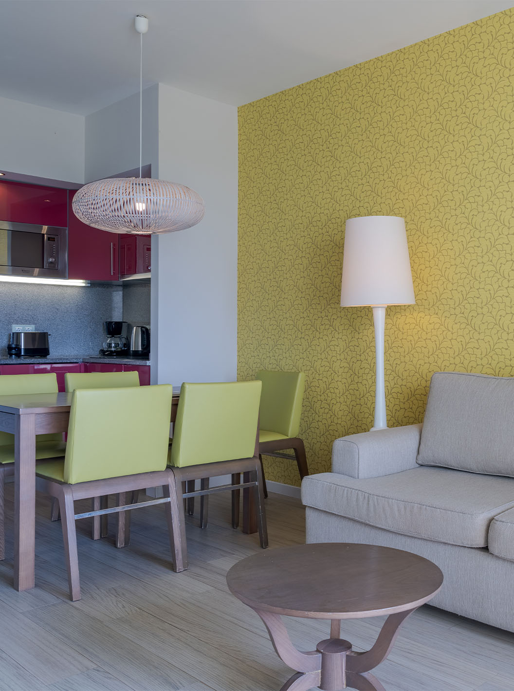 A Suite T1 Vista Jardim do Pestana Alvor Praia tem uma mesa de jantar com cinco cadeiras verdes e um sofá com mesa de apoio