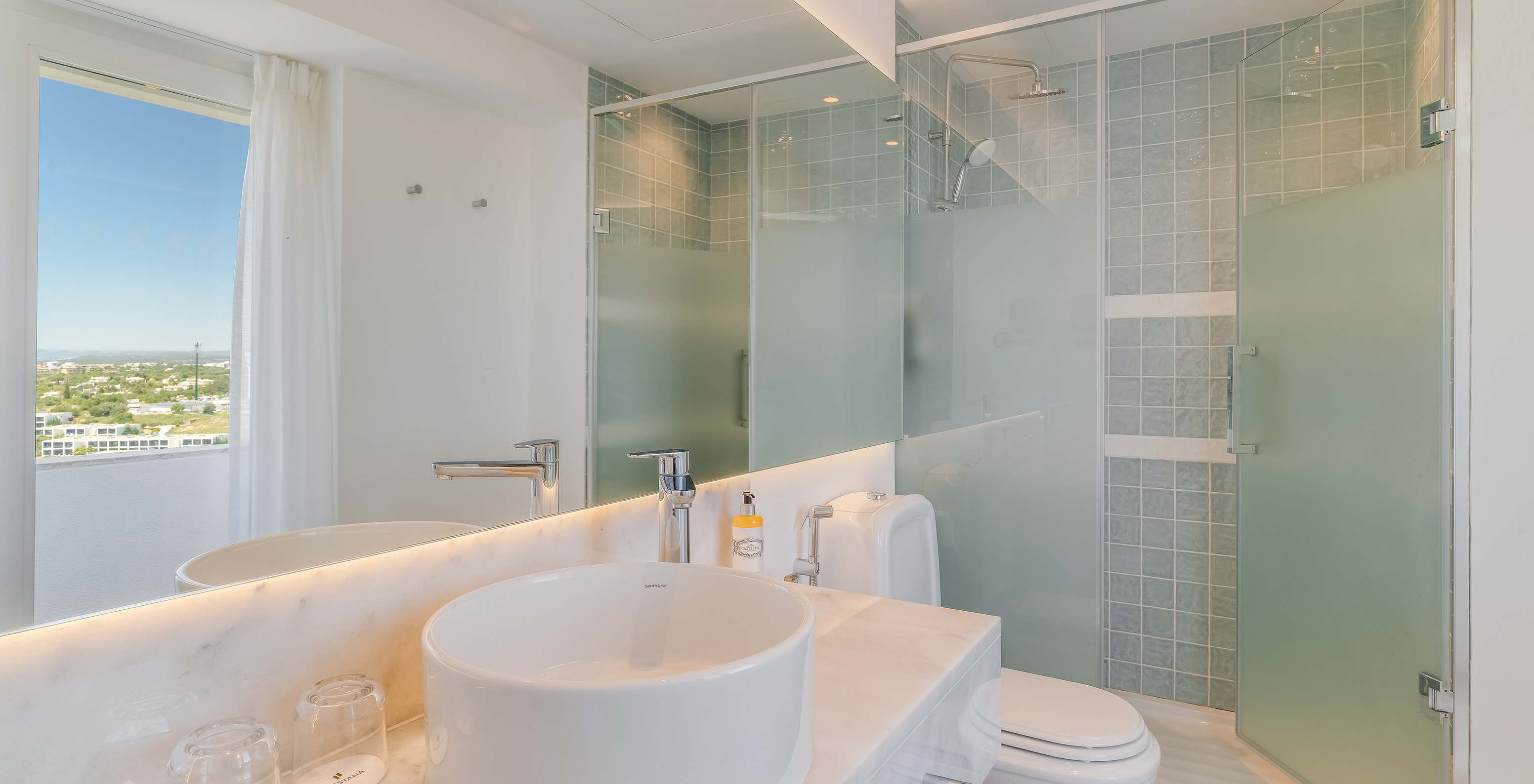 O Quarto Clássico Vista Jardim do Pestana Blue Alvor Beach tem uma casa de banho com lavatório com espelho, sanita e duche