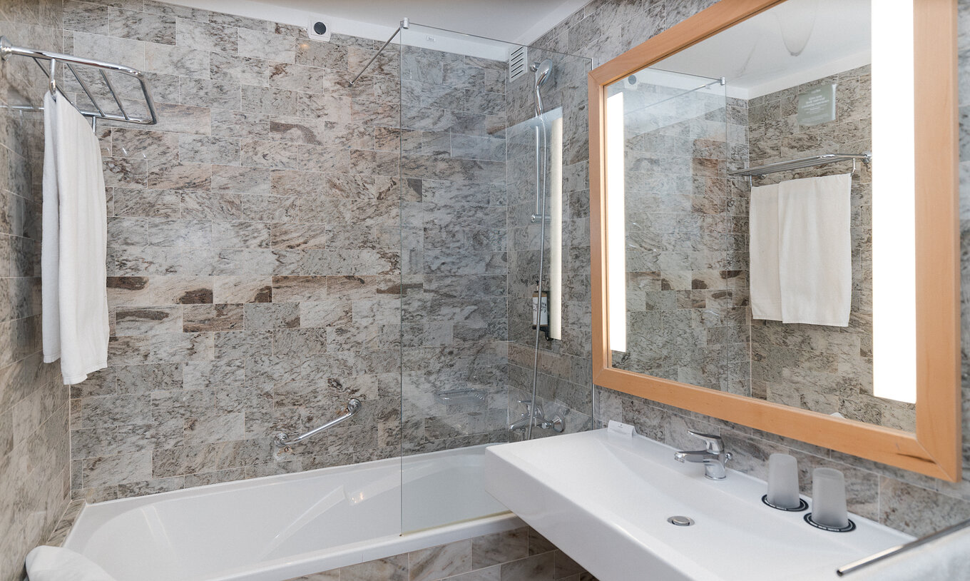 A Suite Superior Vista Mar do Pestana Viking tem uma casa de banho com lavatório com espelho grande e uma banheira com duche