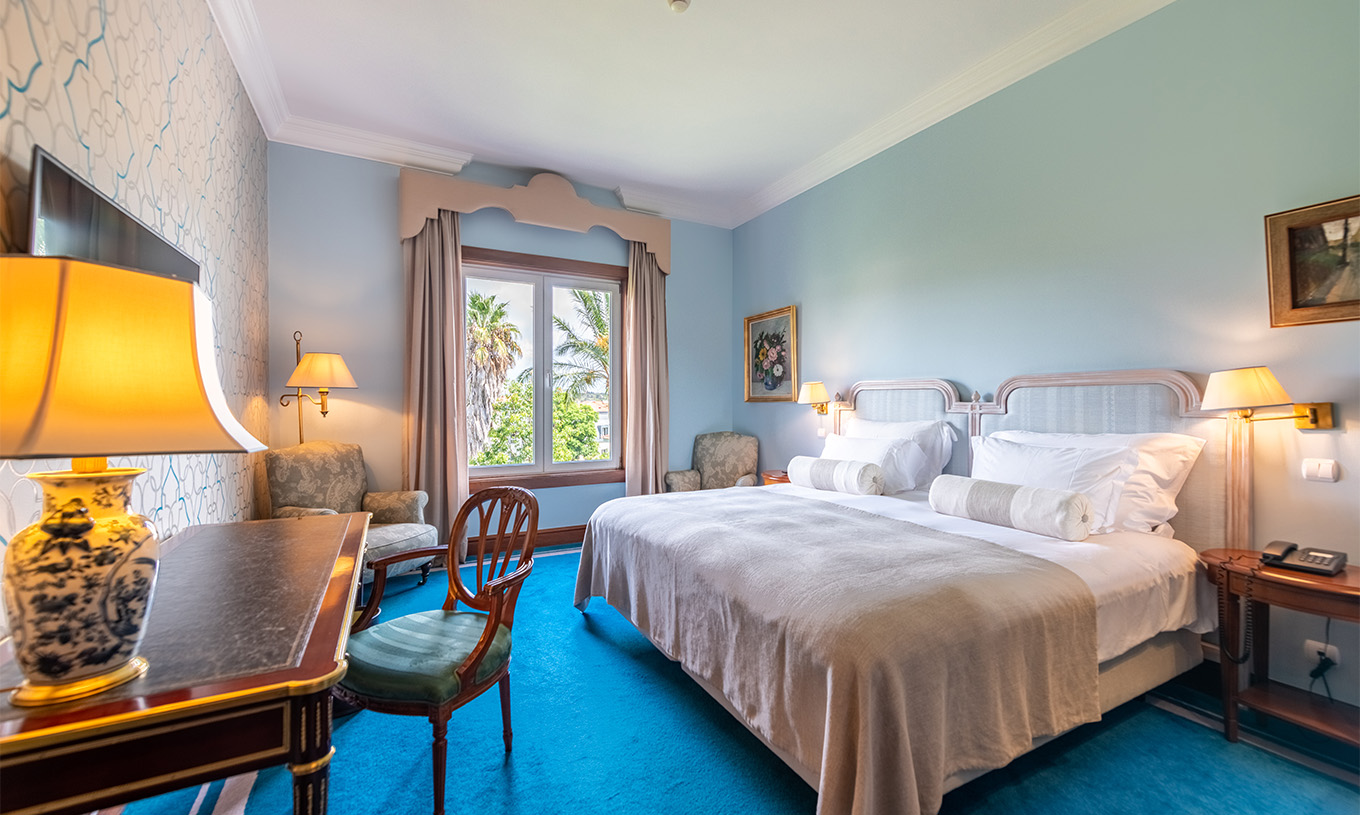 O Deluxe Garden do Pestana Palace Lisboa tem uma cama de casal, duas mesas de cabeceira, secretária e janela com vista jardim