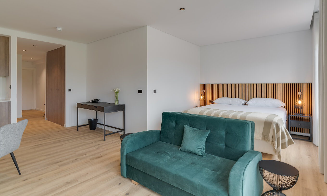 O Familiar com Varanda - Clubhouse do Pestana Sintra Golf tem uma cama de casal com cabeceira em madeira, um sofá e uma mesa