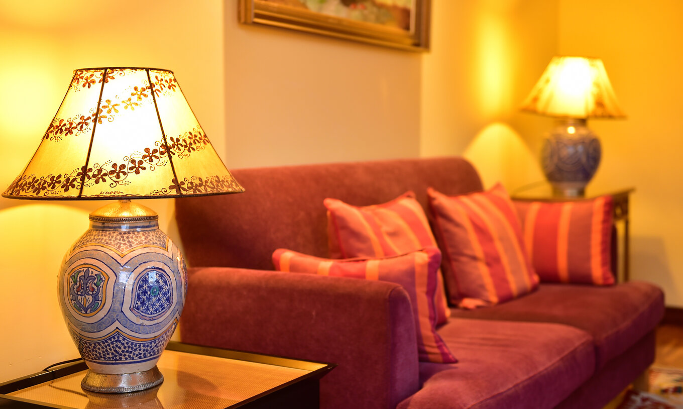 A Suite Superior do Pestana Sintra Golf tem um sofá de dois lugares em tom vermelho e duas mesas com candeeiros