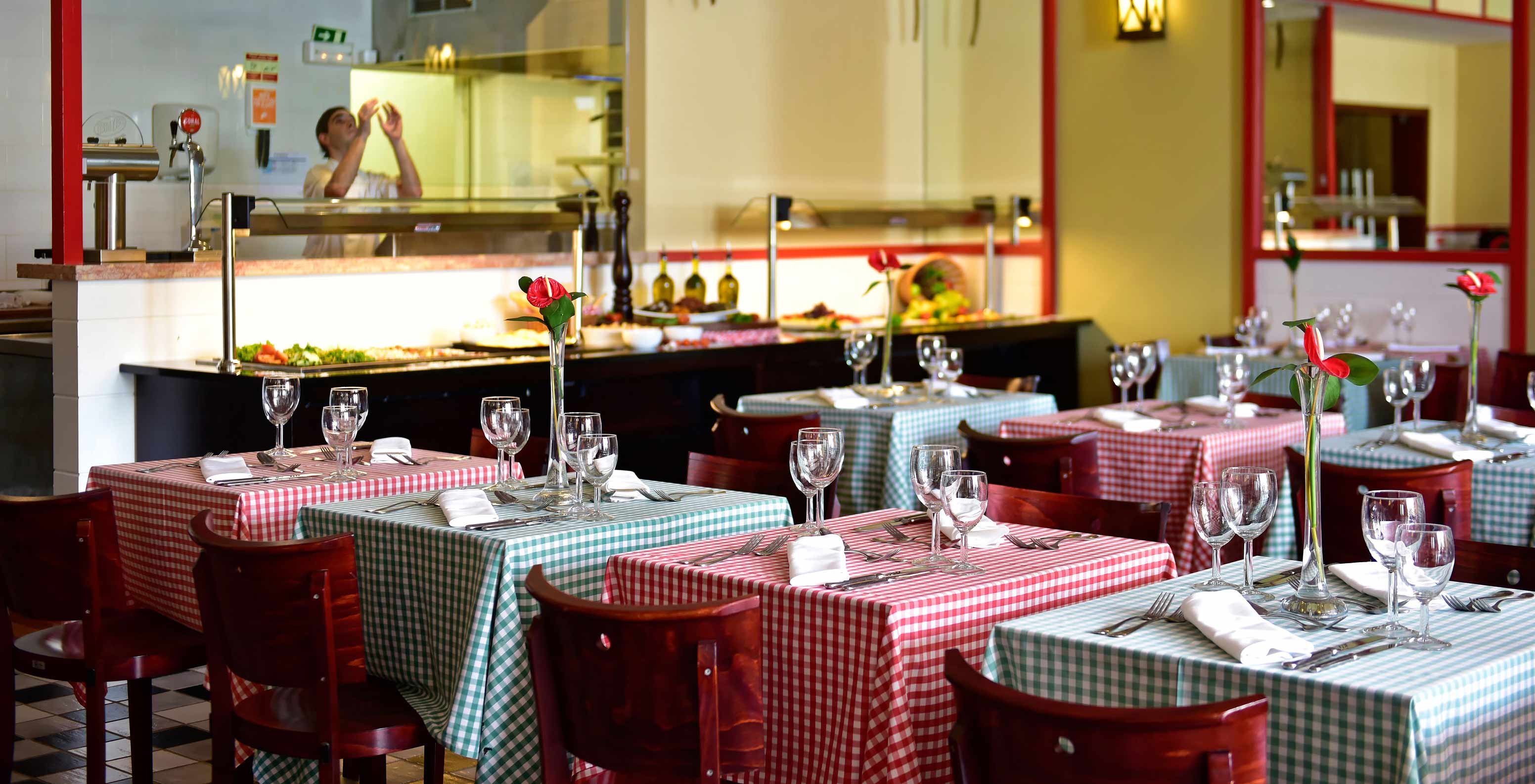 O restaurante Luigi, do Resort de 5 Estrelas no Porto Santo tem um espaço amplo com mesas com toalhas vermelhas e verdes