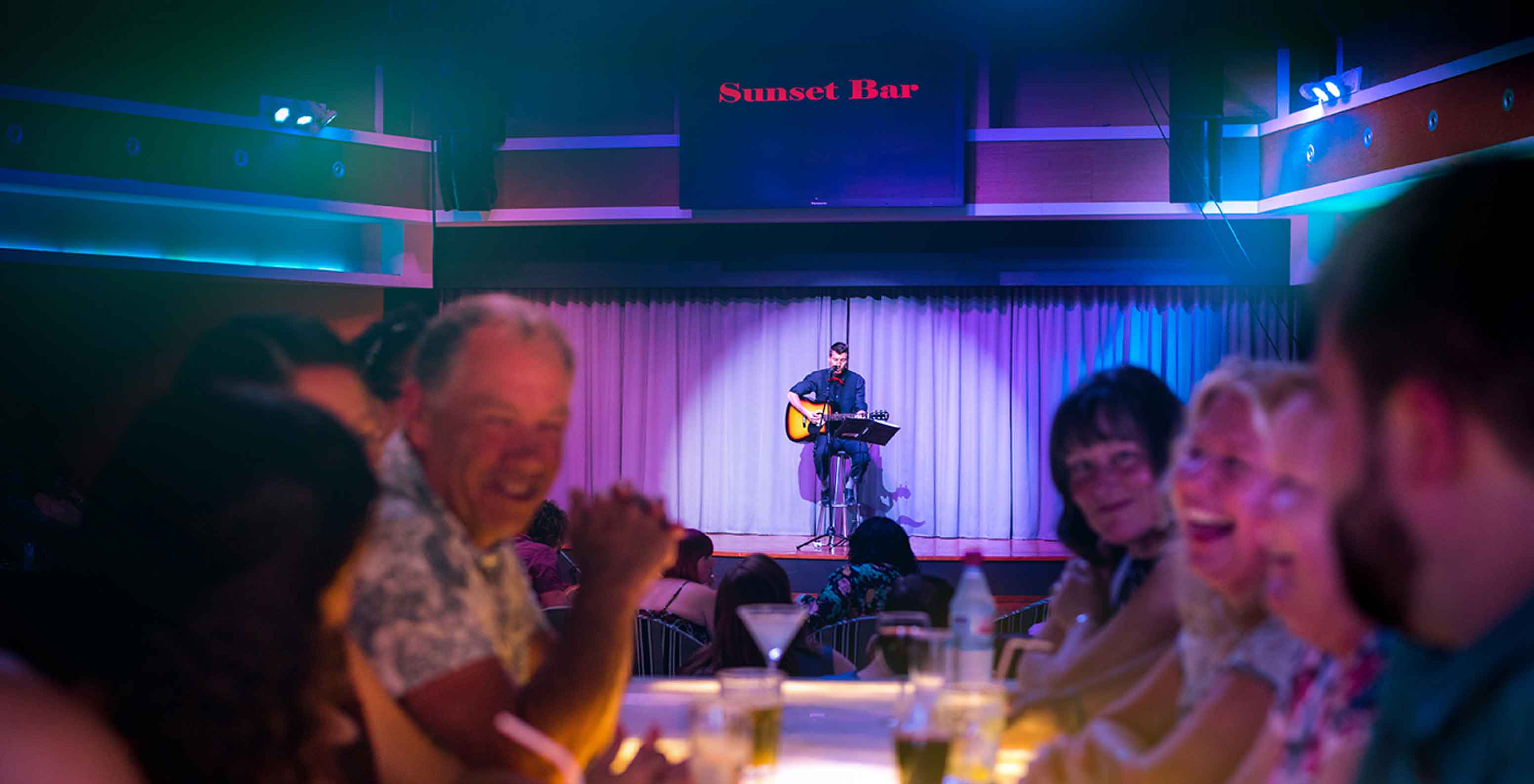 O Sunset Bar,  Resort de 5 Estrelas no Porto Santo tem um palco com um senhor a cantar e pessoas a observar