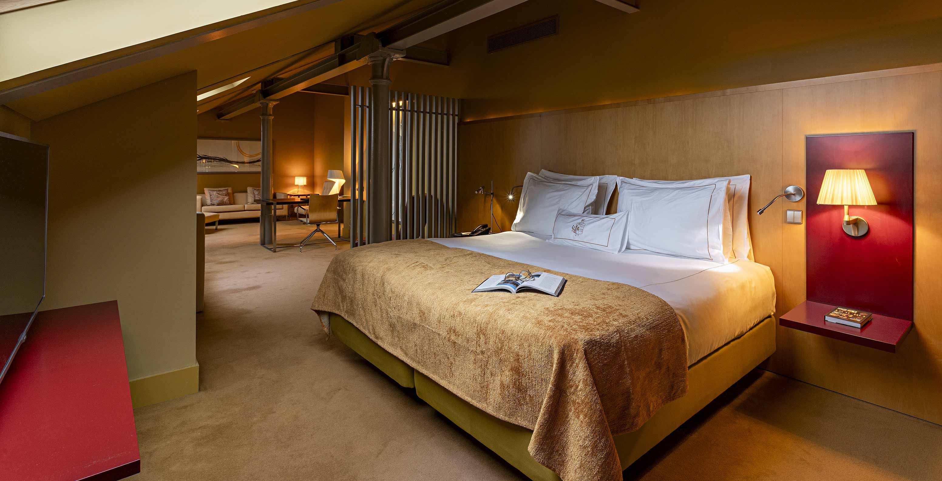 O Loft Ático do Pestana Palácio do Freixo tem um quarto em tom amarelo torrado com cama de casal e poltrona