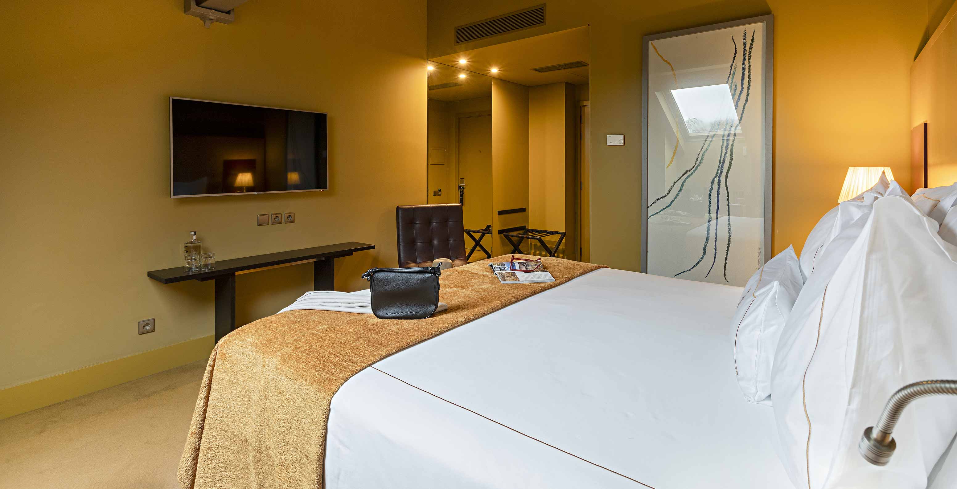 O Clássico Ático do Pestana Palácio do Freixo tem uma cama de casal com uma televisão à frente e uma mesa com água