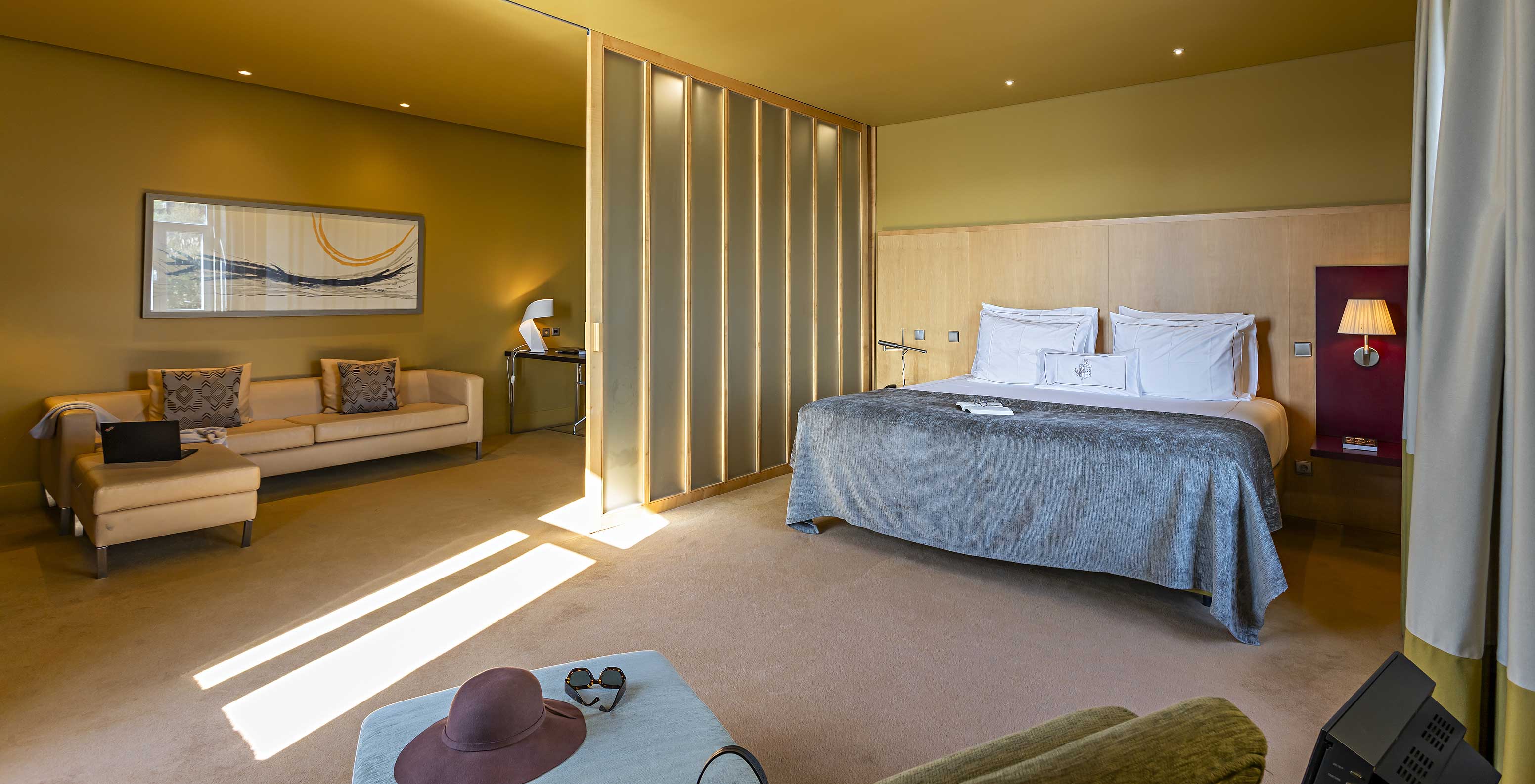 A Standard Suite do Pestana Palácio do Freixo tem uma cama de casal grande com uma manta cinzenta e um sofá