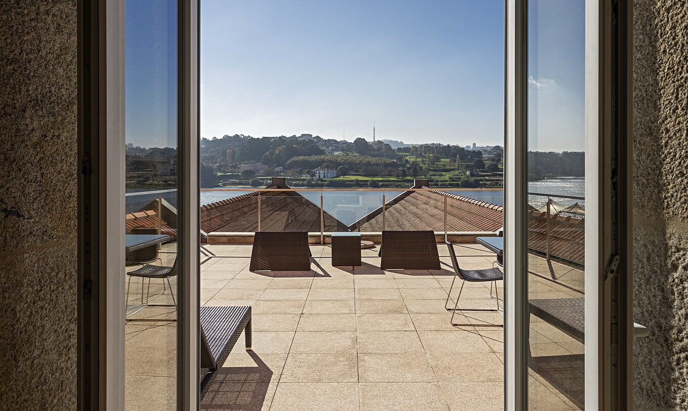 A Suite Nasoni do Pestana Palácio do Freixo tem uma varanda grande com duas mesas e cadiras e expreguiçadeira
