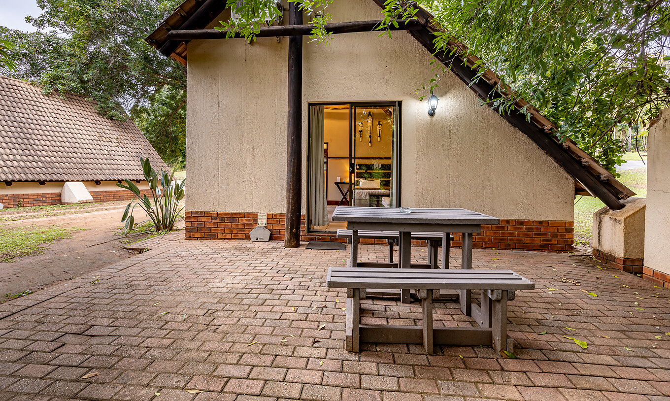 O Quarto Familiar do Pestana Kruger Lodge tem uma zona exterior com uma mesa corrida de madeira, com vista para o jardim