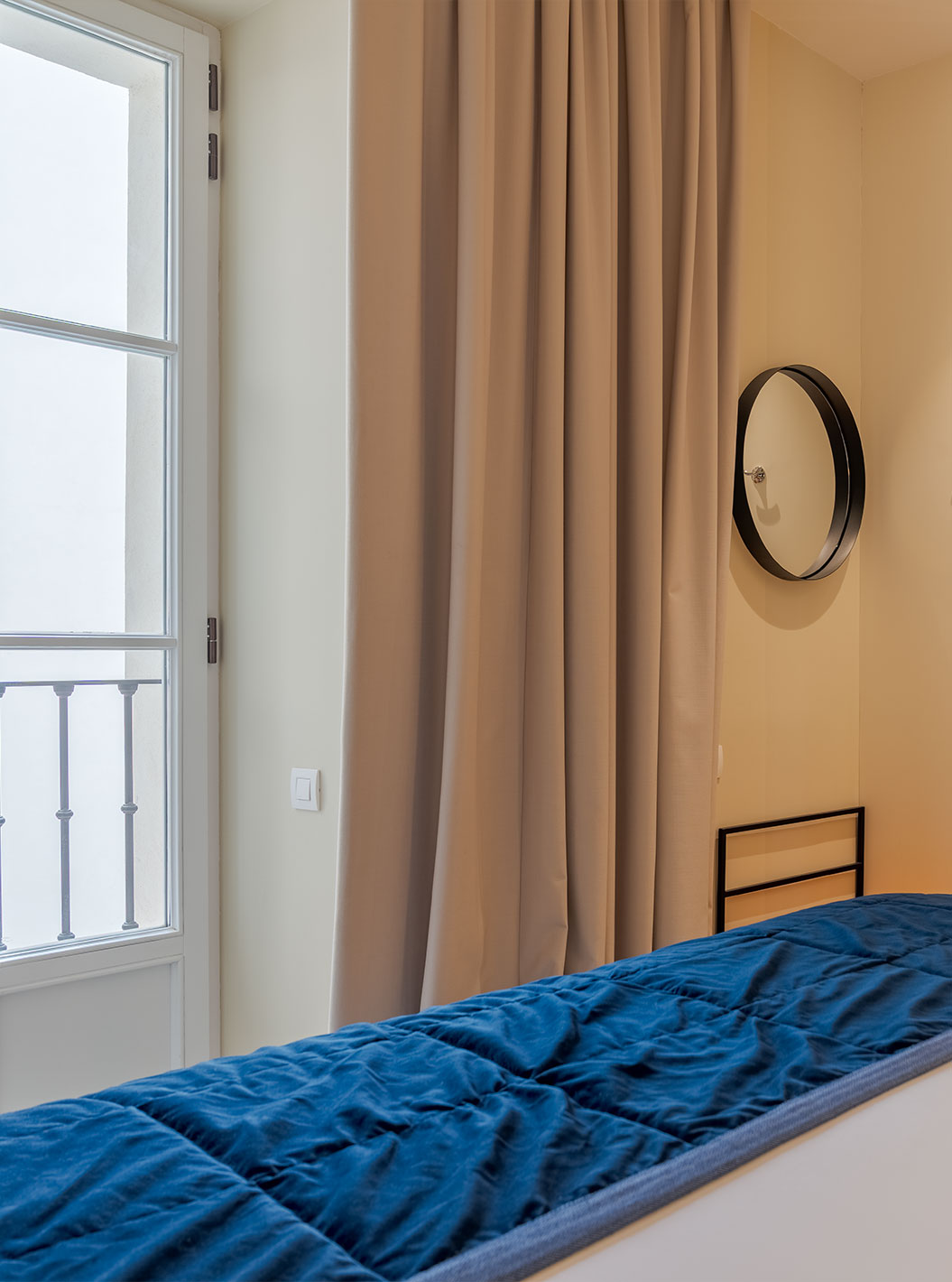 Suíte do Pestana Collection Plaza Mayor com cama, cortinas longas e banheiro integrado junto à janela