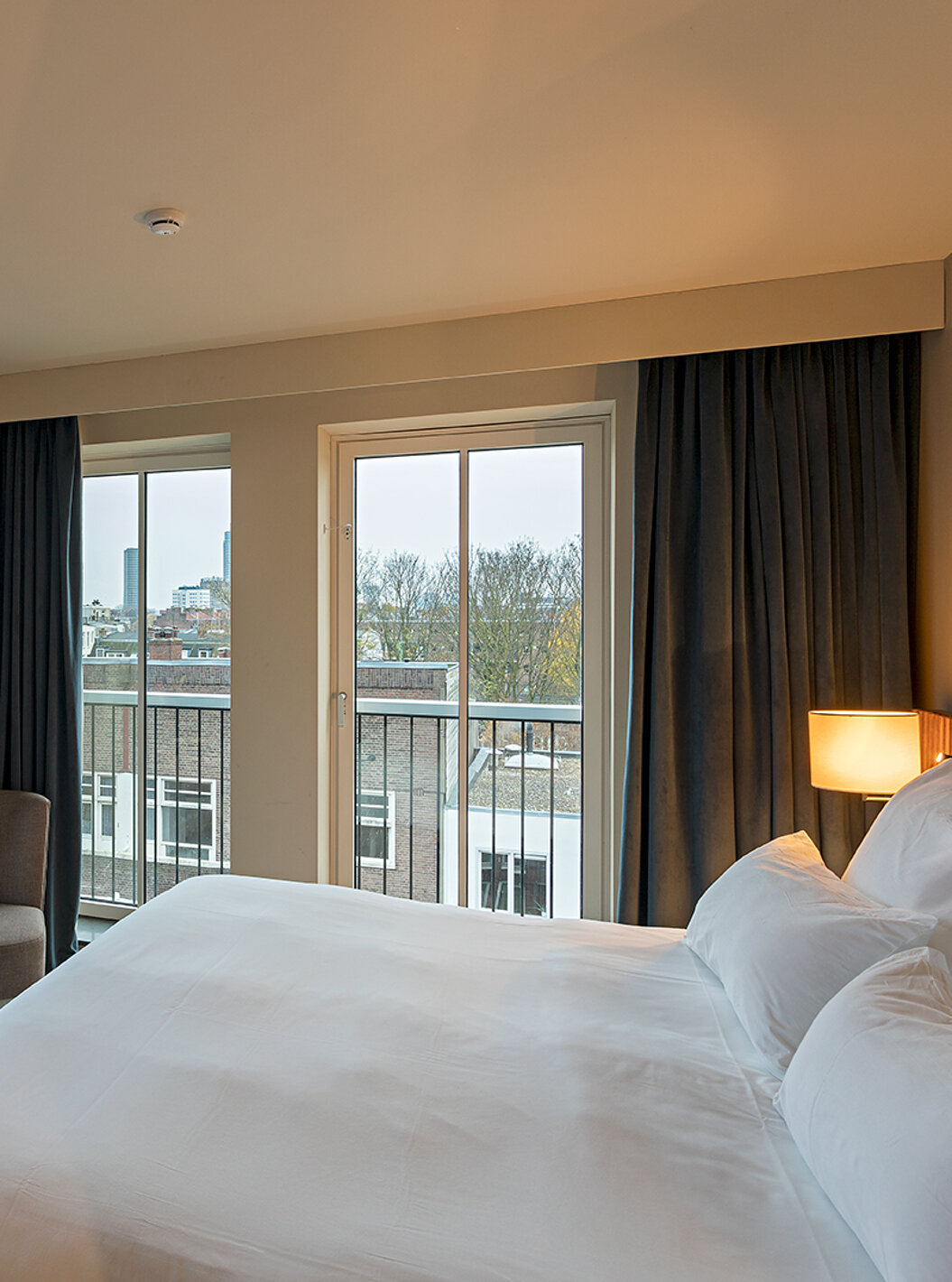 O quarto Estúdio Clássico do Pestana Amsterdam Riverside tem uma cama de casal, um candeeiro e janelas com vista para a rua