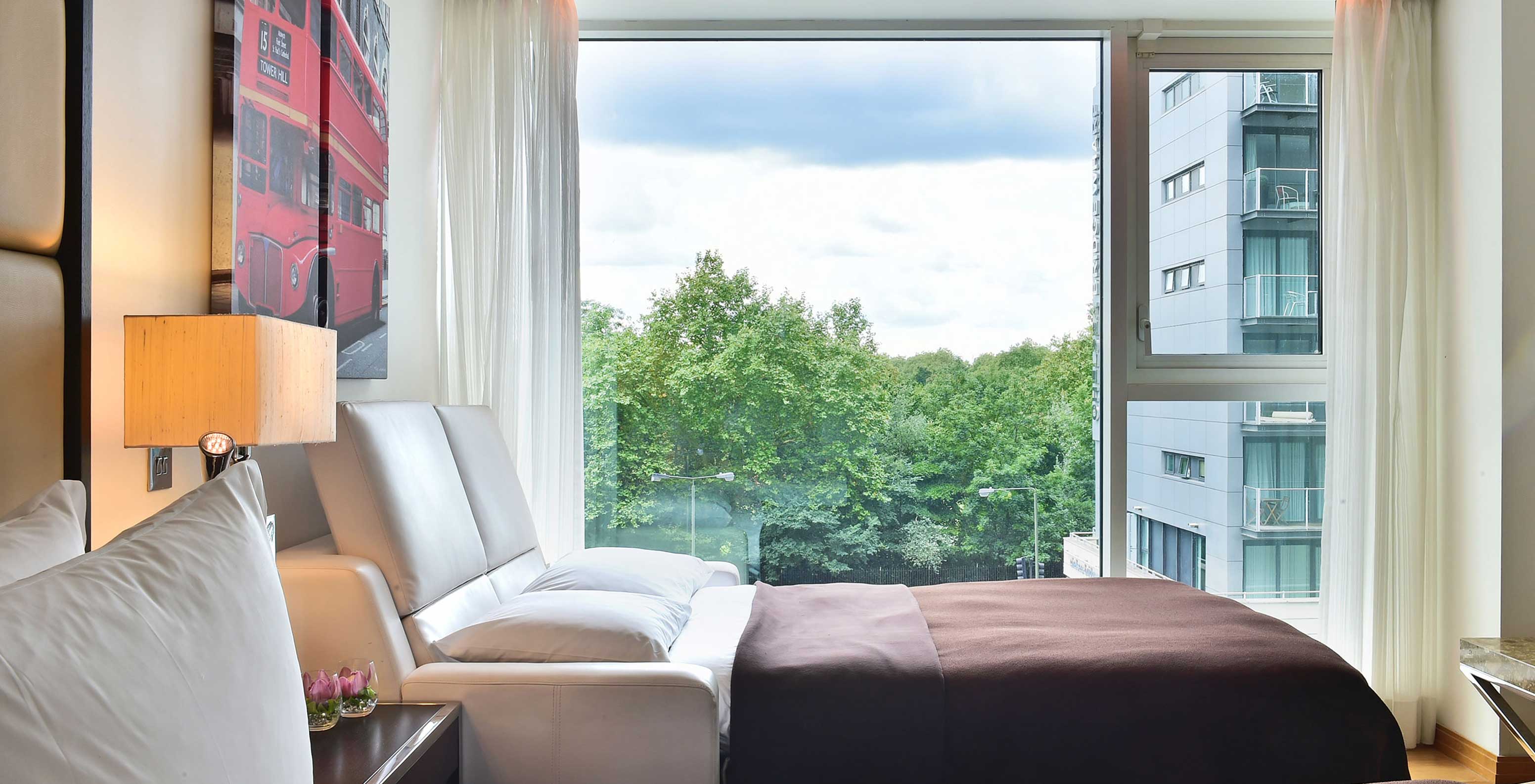 O Deluxe Family do Pestana Chelsea Bridge tem sofá cama aberto, quadros de londres e janela grande com vista e cortinas