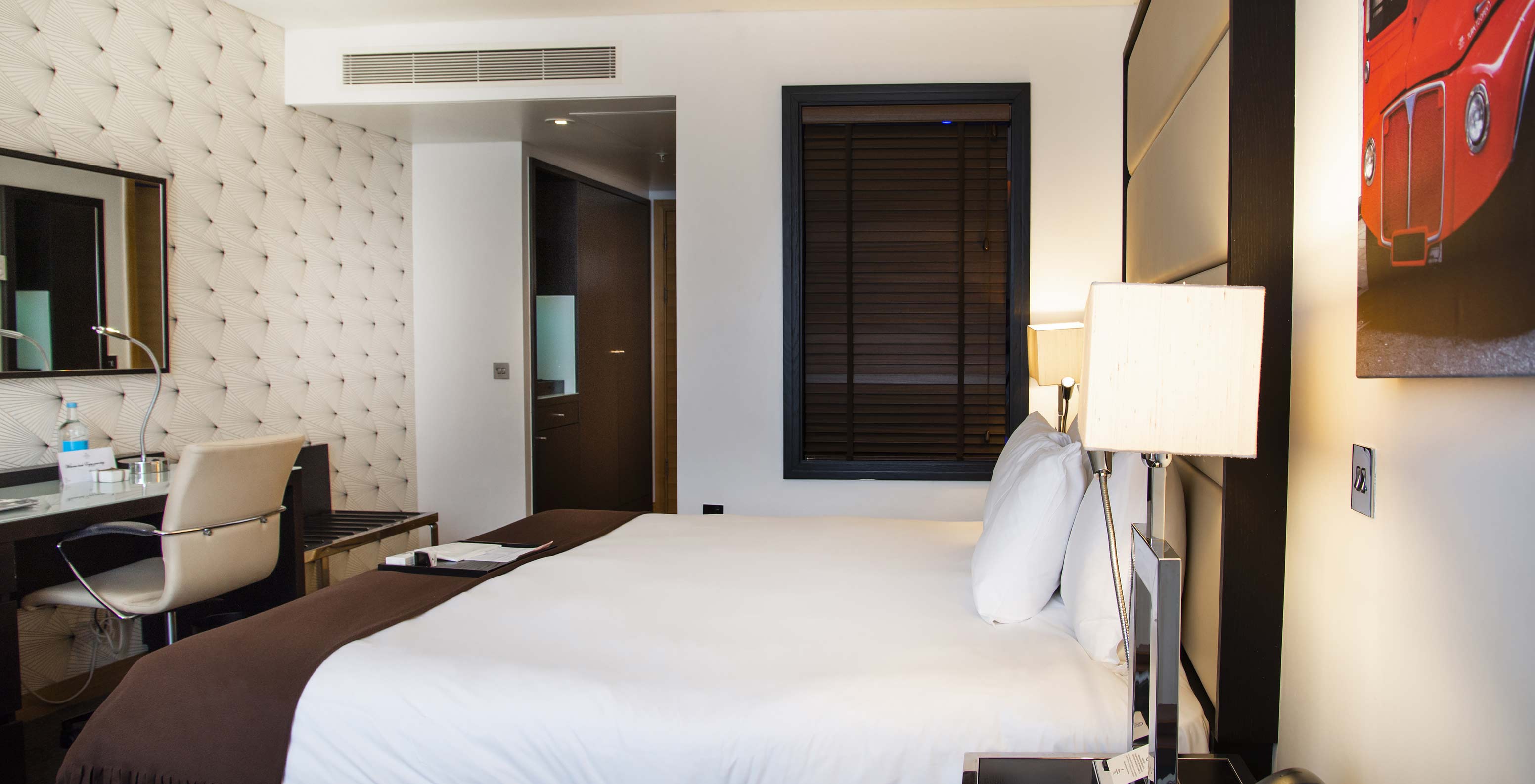O Premium King do Pestana Chelsea Bridge tem cama de casal com lençóis brancos, secretária com cadeira e um espelho