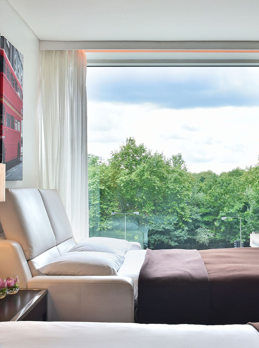 O Deluxe Family do Pestana Chelsea Bridge tem sofá cama aberto, quadros de londres e janela grande com vista e cortinas