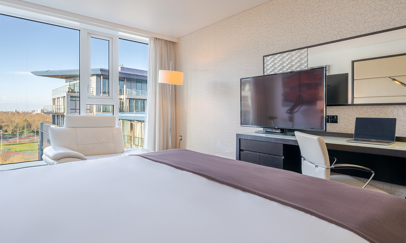 O Deluxe Premium King do Pestana Chelsea Bridge tem cama de casal, uma secretária com televisão, sofá e janelas para a cidade