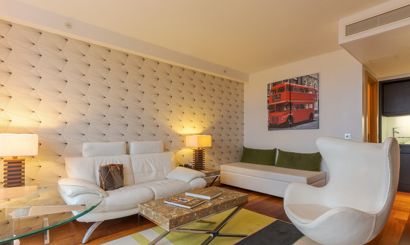 A Executive One Bedroom Suite do Pestana Chelsea Bridge tem um sofá e um pufe com mesa de centro, mesa de vidro e poltrona