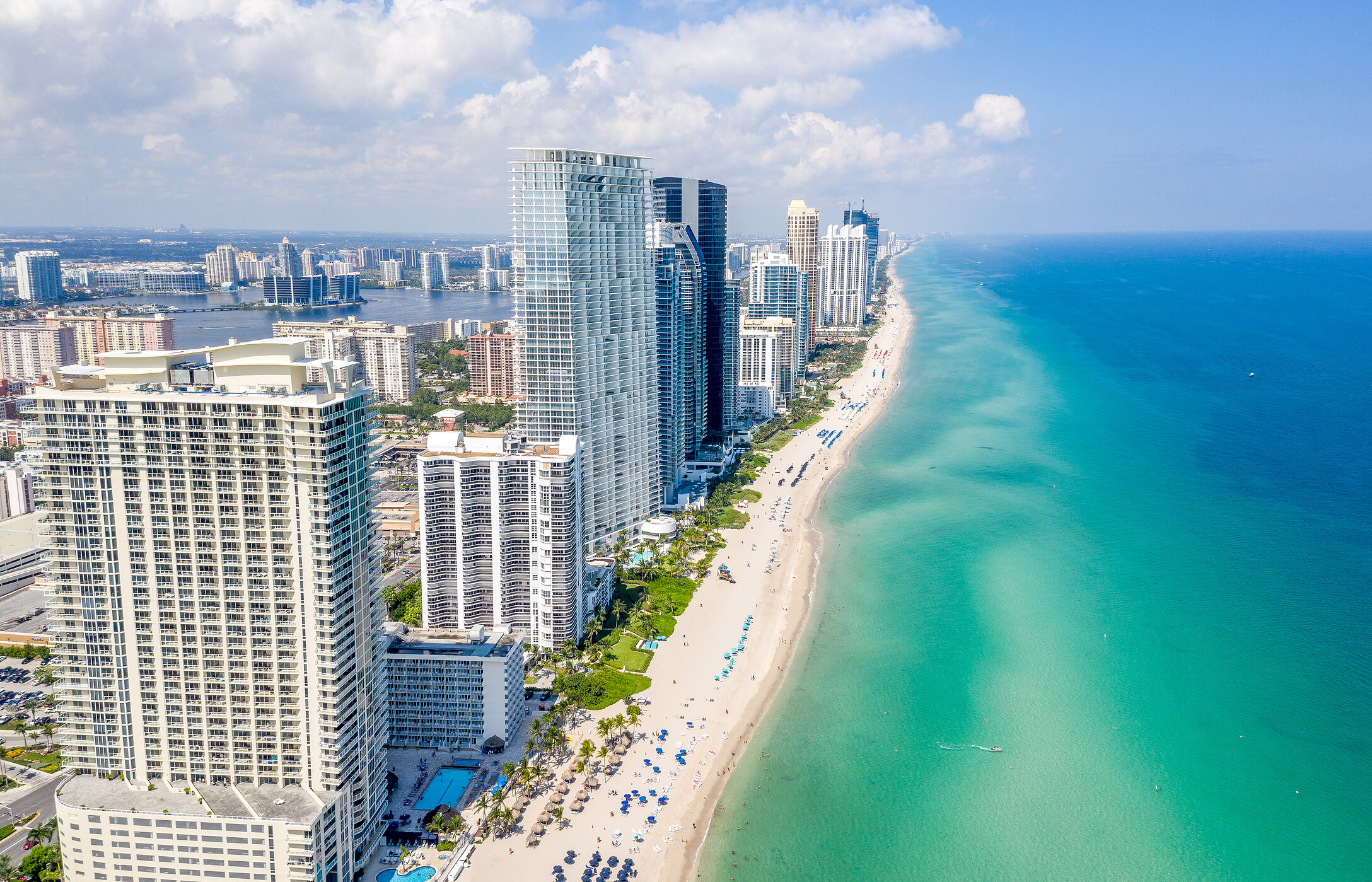 Vista aérea da costa de Miami Beach, na Florida, com uma longa faixa de areia branca, água cristalina, e edifícios altos