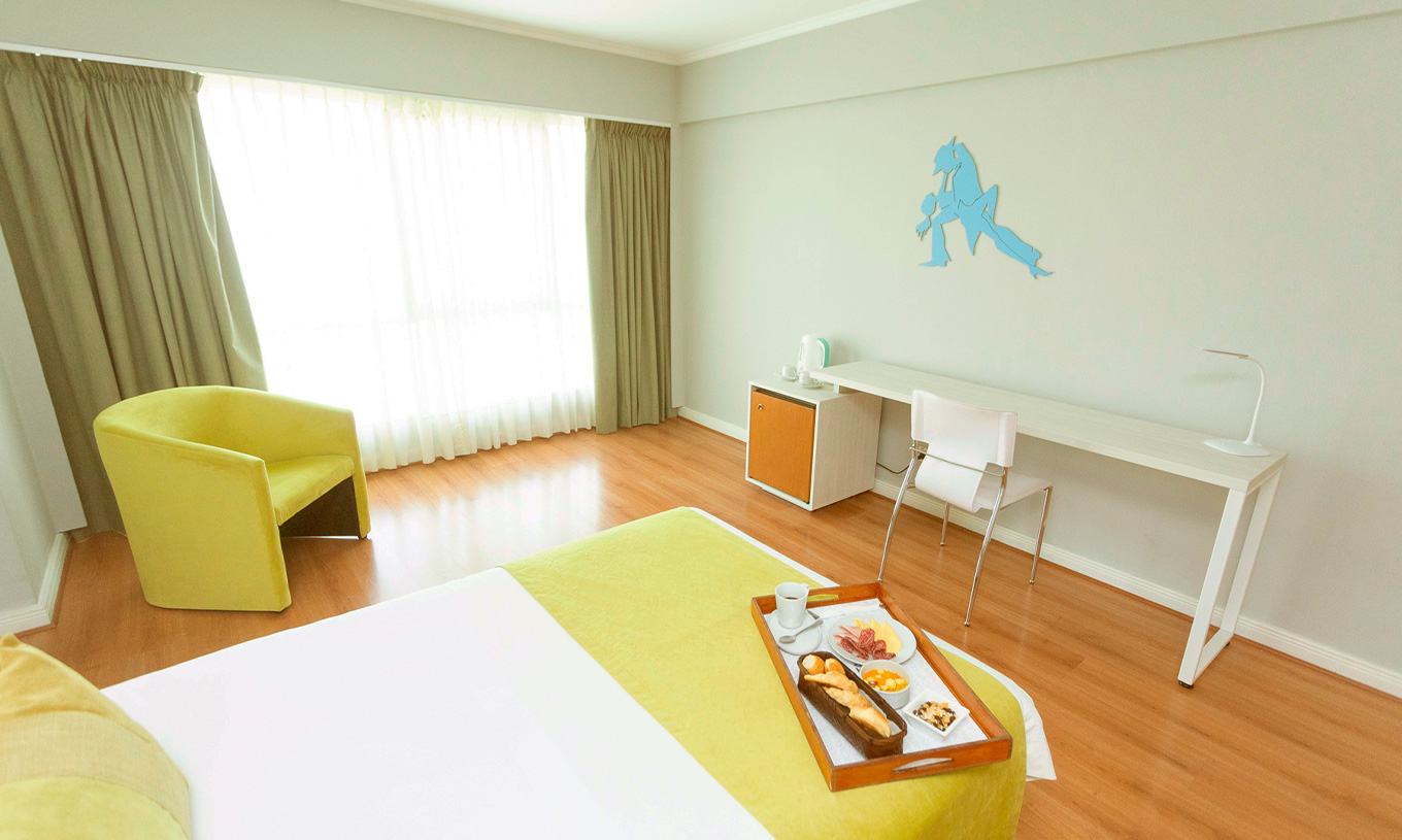 O quarto Queen Executive do Pestana Buenos Aires conta com uma cadeira, uma secretária e elementos de decoração