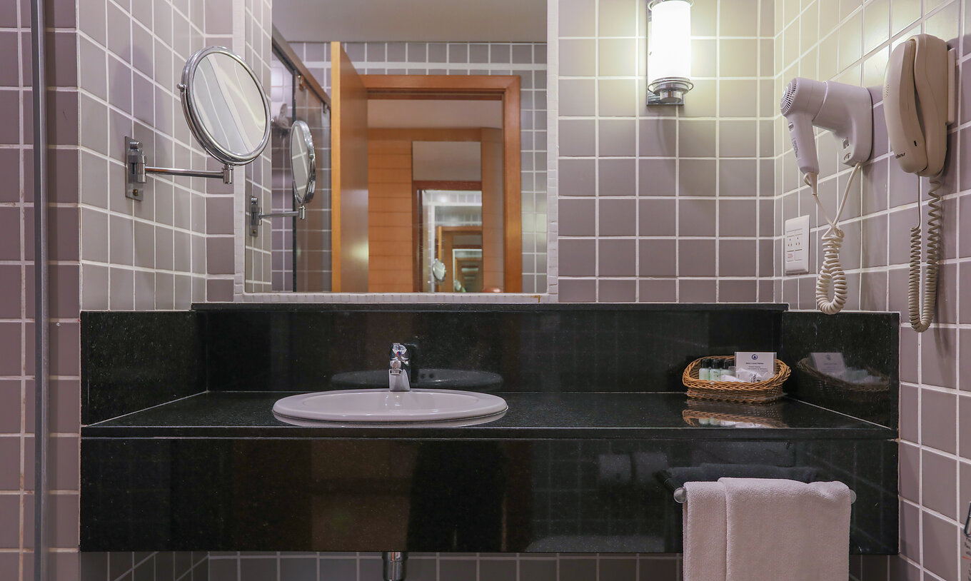 O Queen Luxo Corner do Pestana Curitiba tem uma casa de banho com azulejos cinzentos e uma bancada preta com lavatório