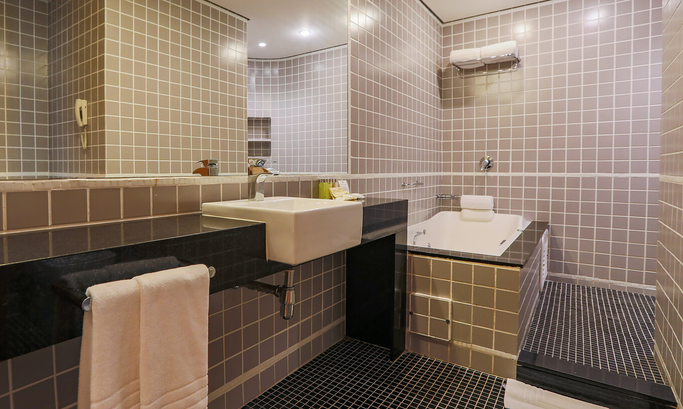 A King Suite Executiva do Pestana Curitiba tem um espaço de duche e uma banheira de hidromassagem