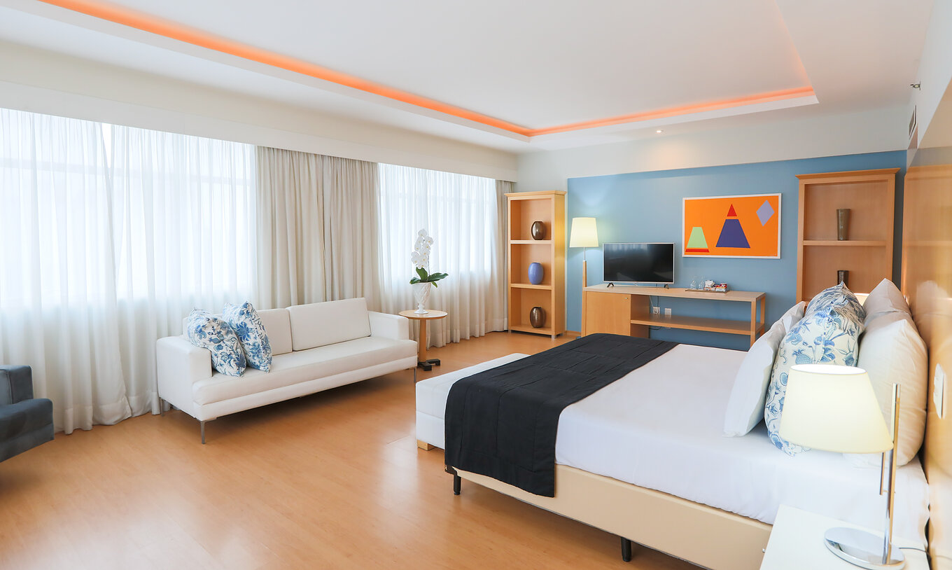 A King Suite Executiva do Pestana Curitiba é um quarto amplo com várias janelas, bastante luminoso, com cama de casal e sofá