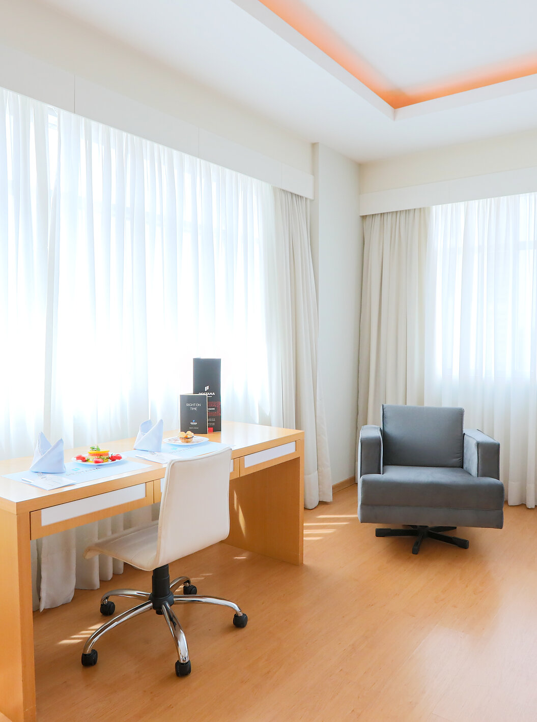 O Queen Luxo Corner do Pestana Curitiba tem sofás e secretária junto a duas janelas grandes que deixam entrar bastante luz