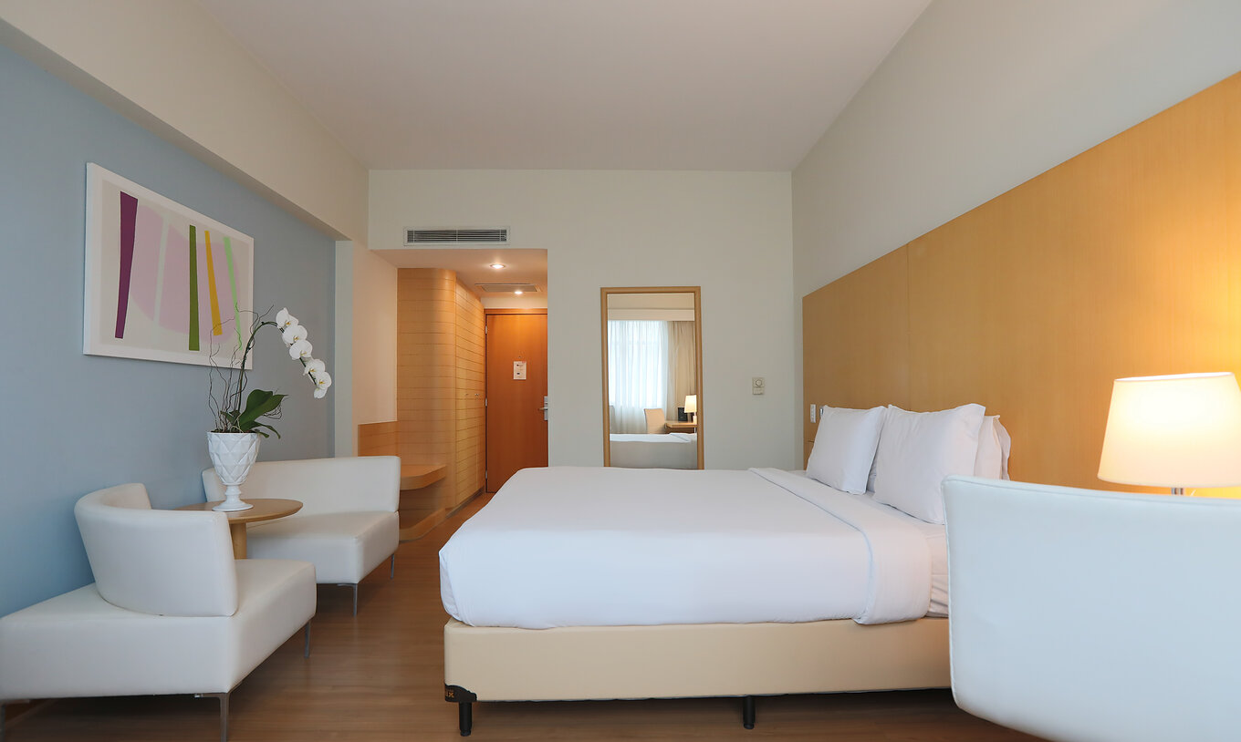 O Queen Superior do Pestana Curitiba tem uma cama de casal e dois sofás individuais ao pés da cama