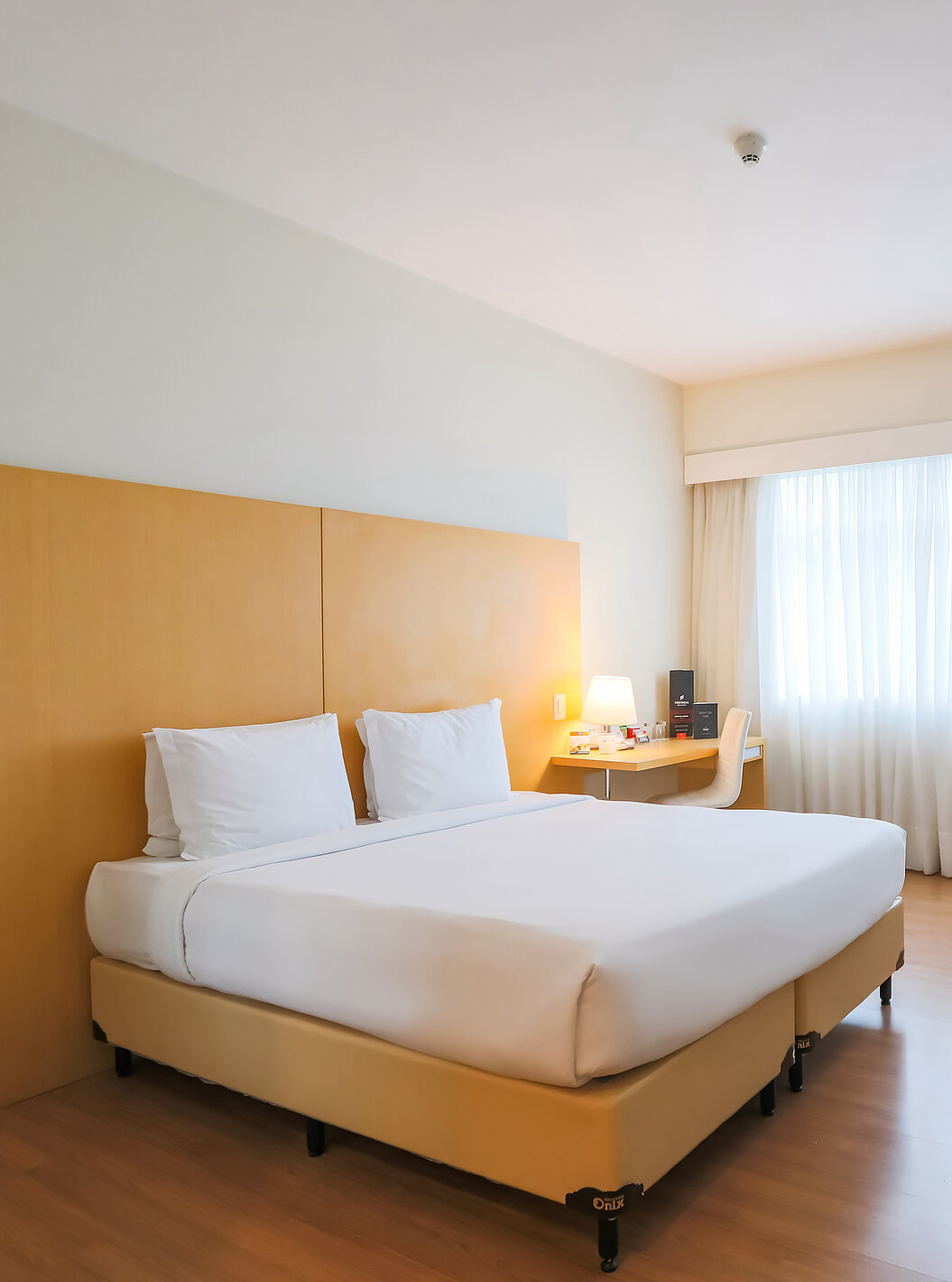 O Queen Superior do Pestana Curitiba tem um quarto com cama de casal, sofás, uma secretária e um móvel com televisão