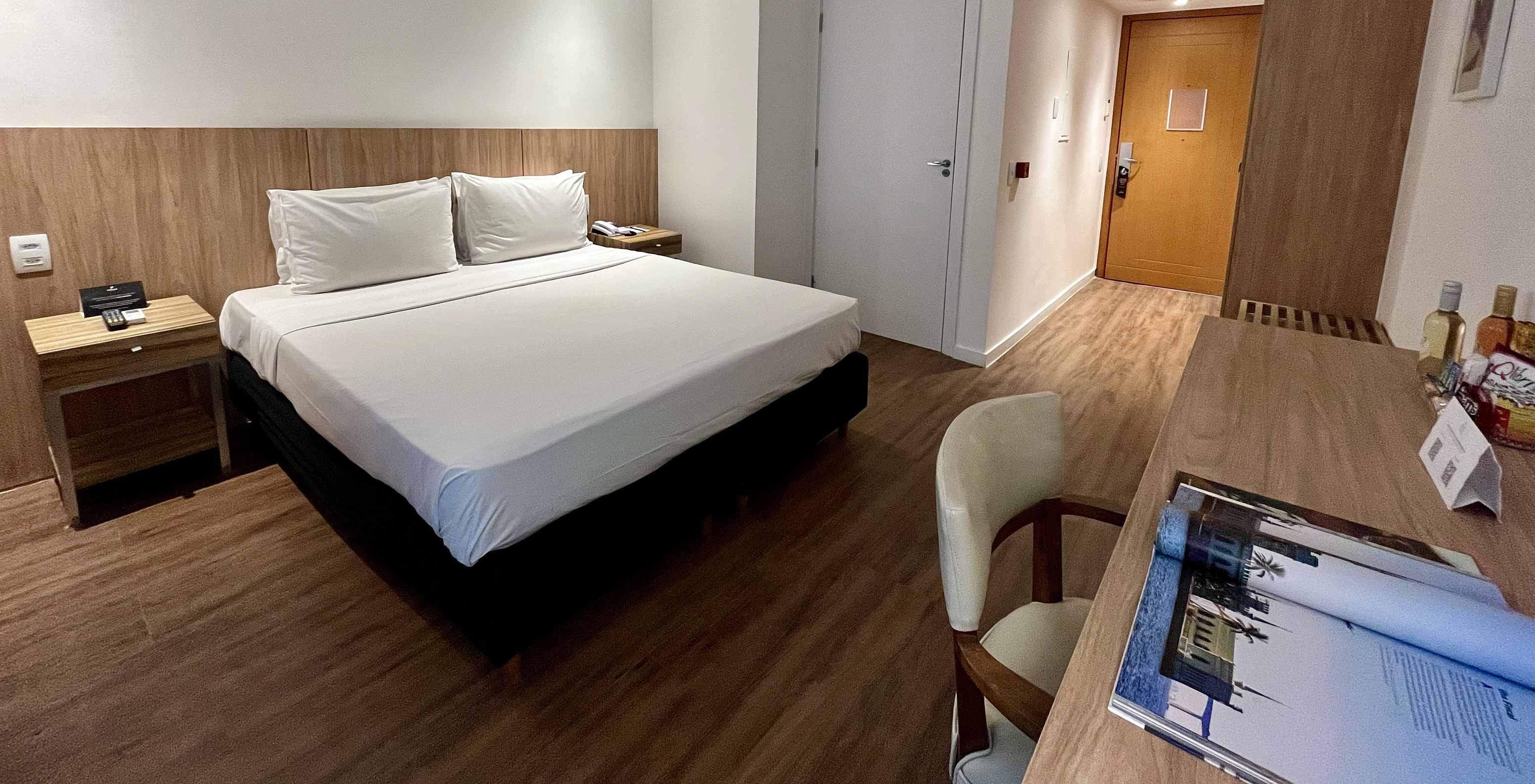 O Quarto Semi Adaptado do Pestana Rio Atlântica é um quarto com cama, secretária, TV na parede e chão em madeira
