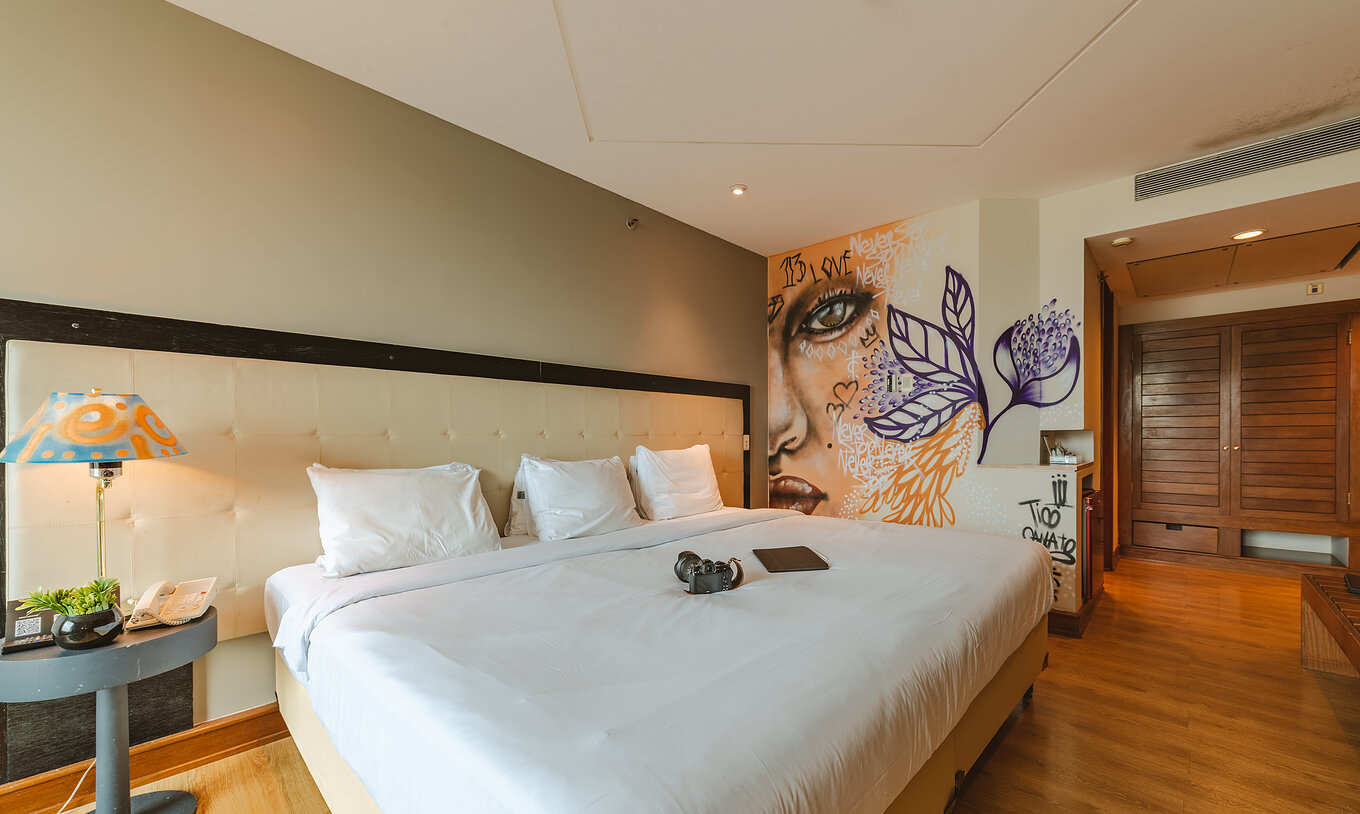 O Art Room do Pestana São Paulo tem uma cama tripla e pinturas na parede e candeeiros do artista Tico Canato