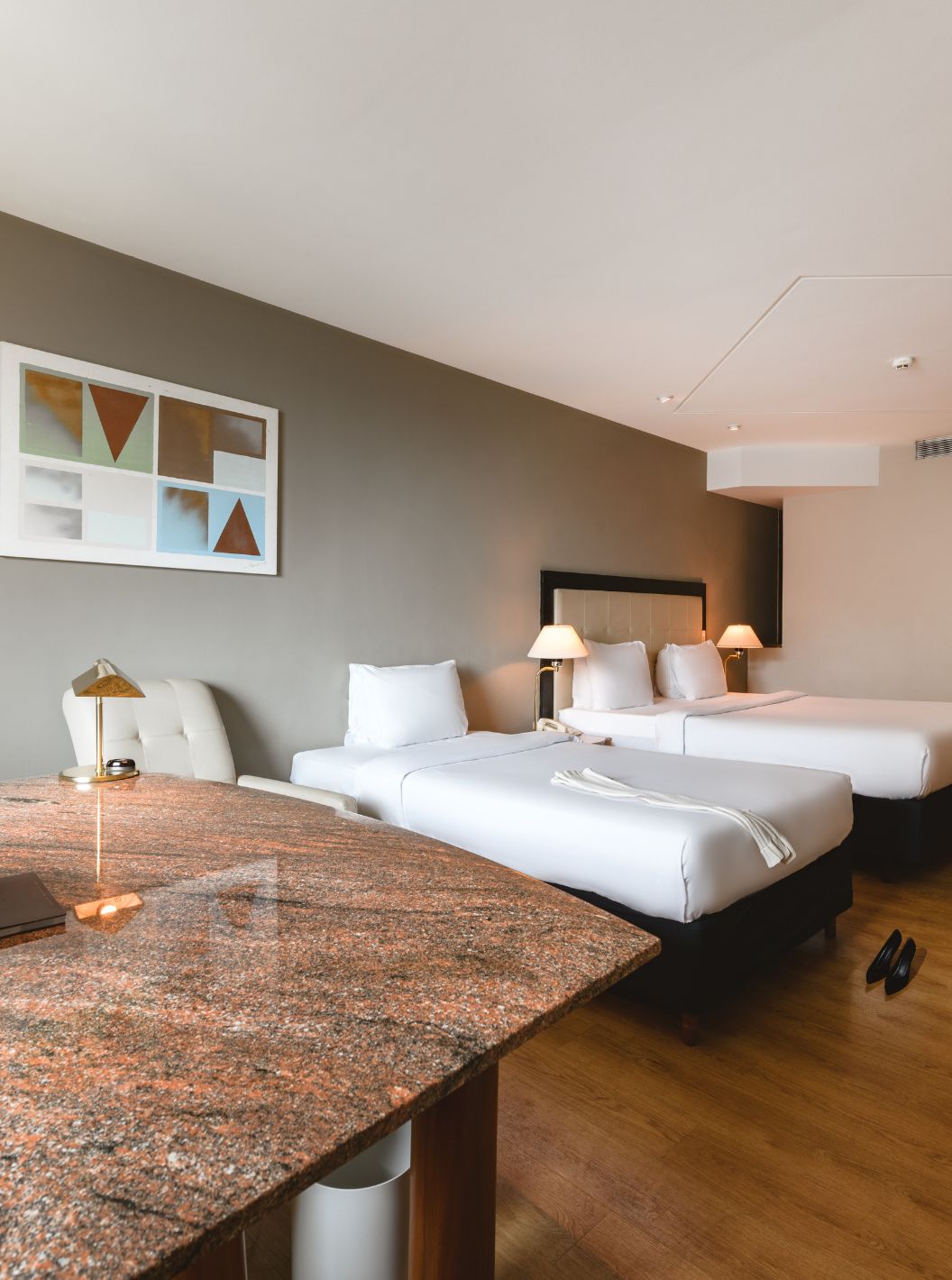 O Quarto Familiar do Pestana São Paulo tem uma secretária em pedra, uma cama de casal e uma cama individual