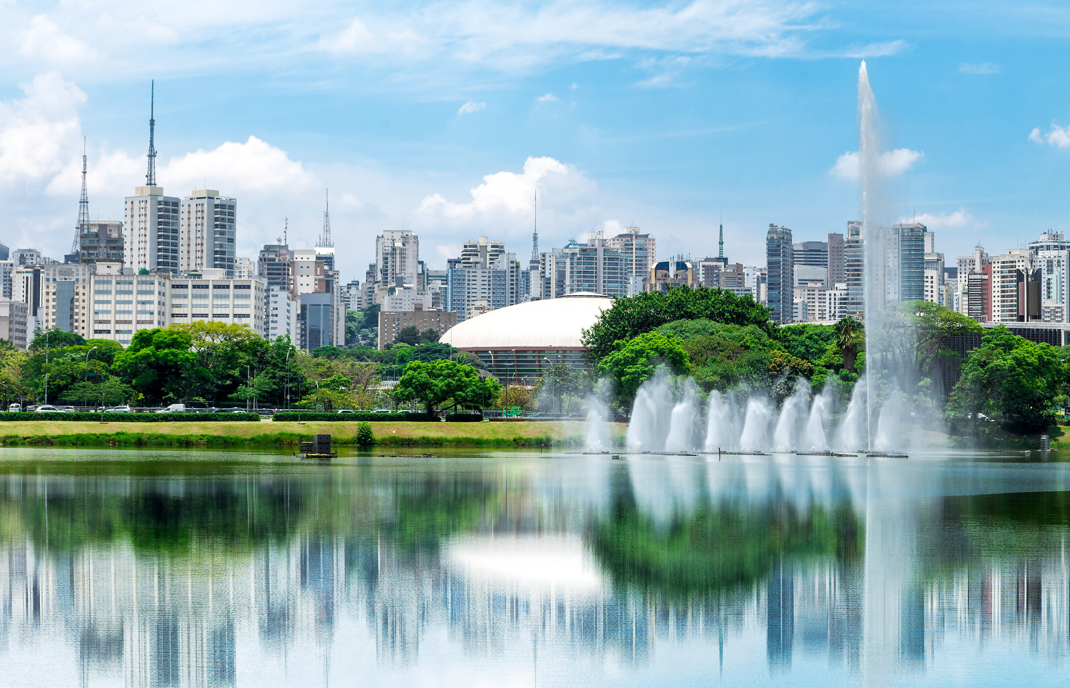 Lago com fonte no Parque Ibirapuera, no centro de São Paulo, com espaços verdes à volta