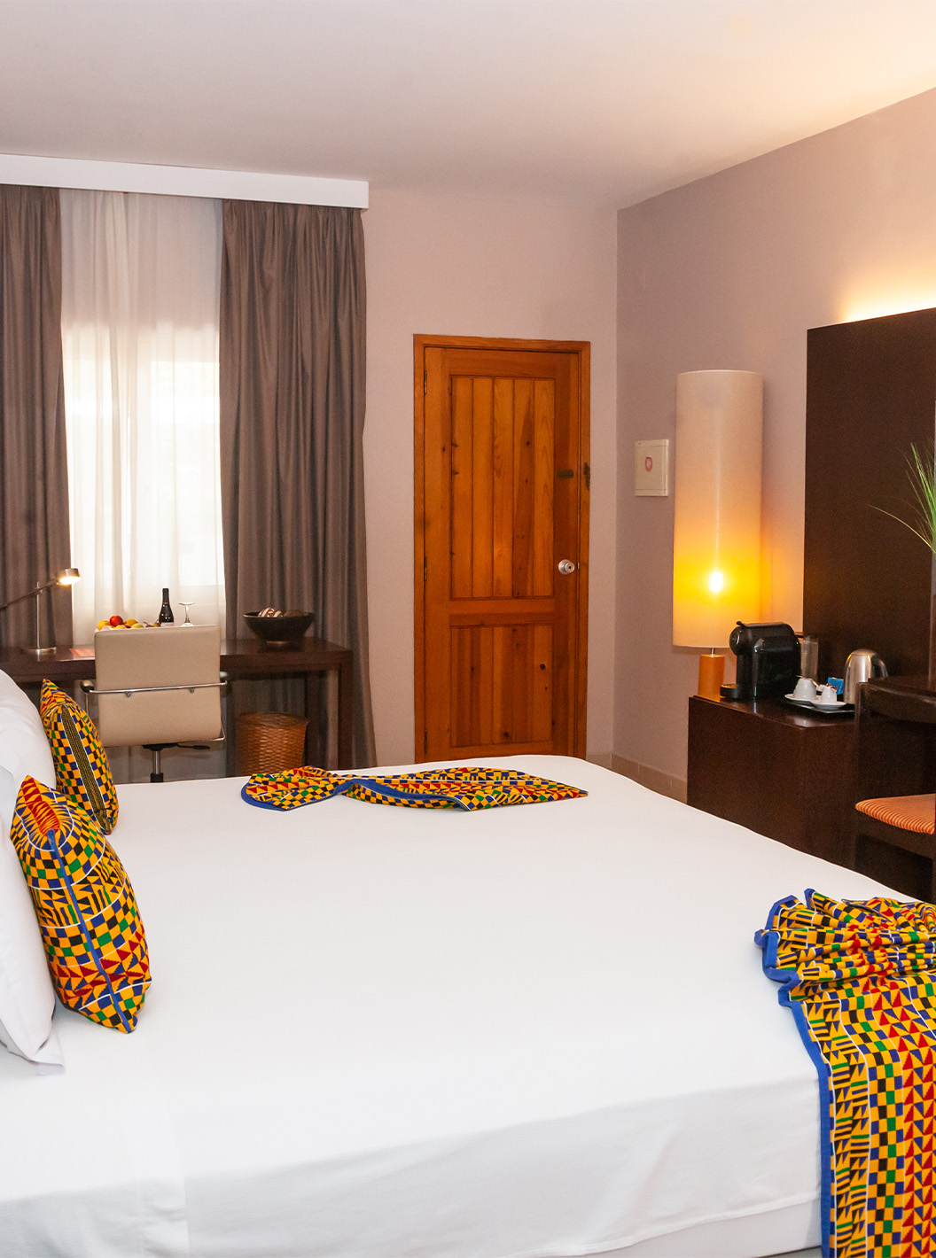 A Junior Suite do Pestana Tropico conta com cama de casal, televisão, espelho e secretária com cadeira e cesto de fruta