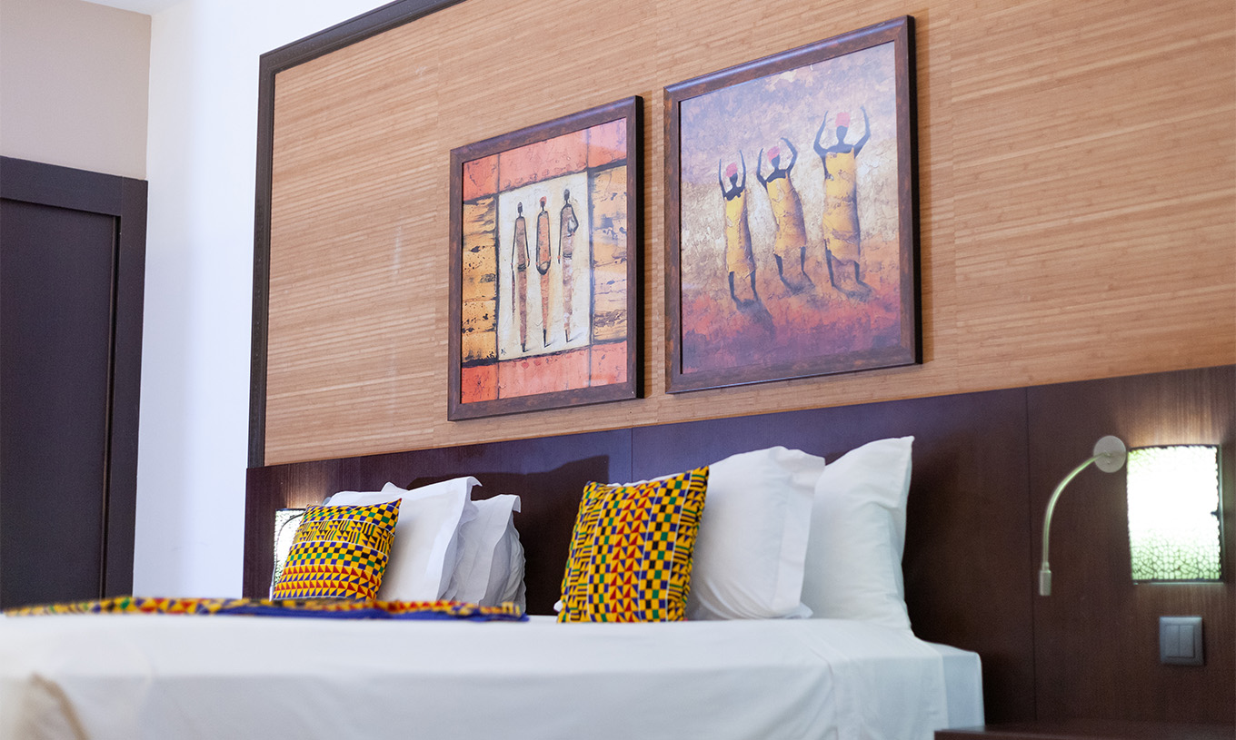 O quarto Premium do Pestana Tropico conta com dois quadros de arte por cima da cama de casal, e uma mesa de cabeceira