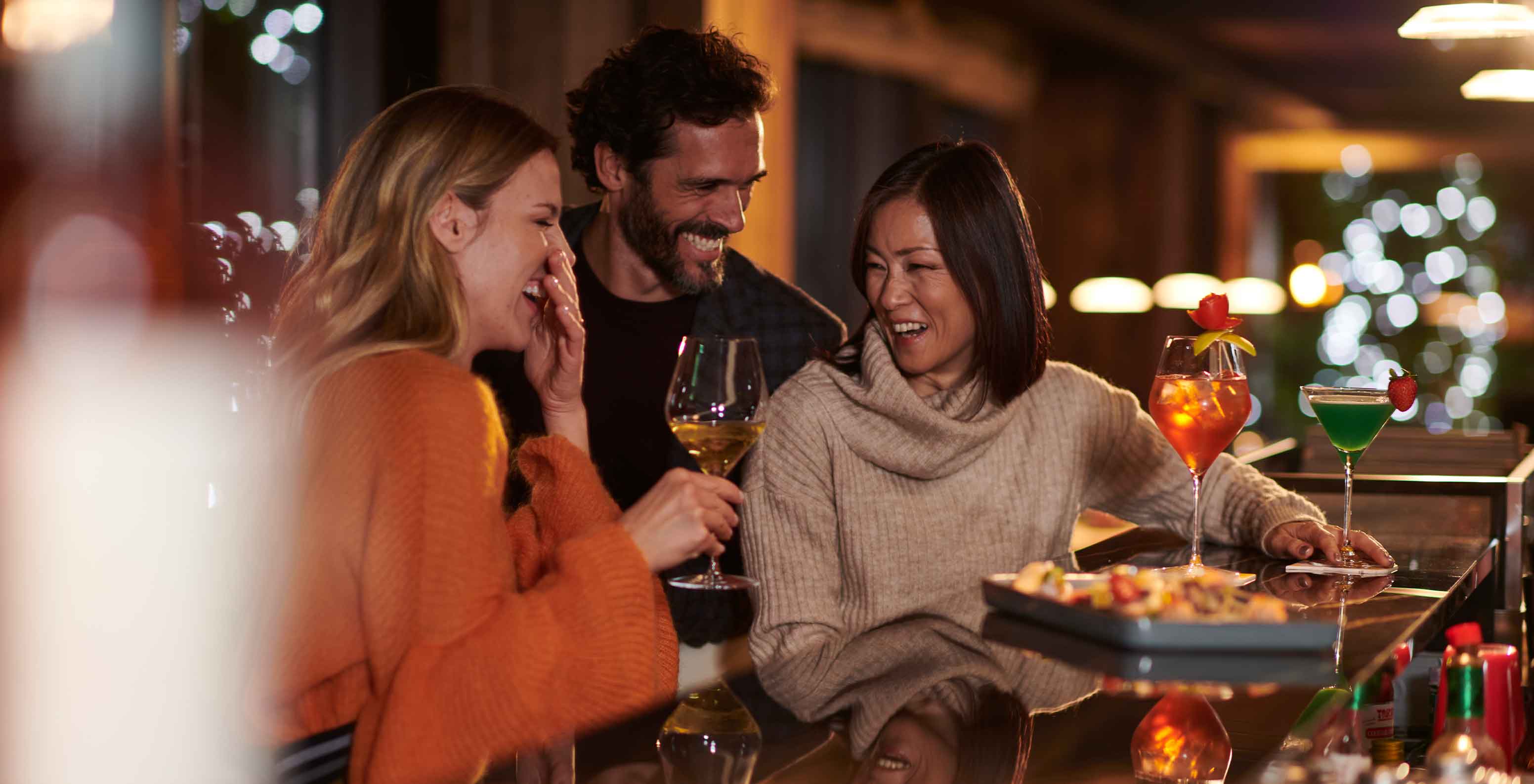 Pessoas sentadas no bar do Le Massif Courmayeur, Hotel nos Alpes Italianos em Courmayeur para fazer ski, com cocktails coloridos sobre o balcão
